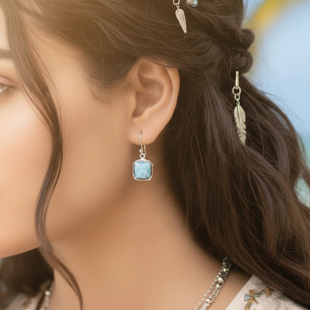 Sterling silver dangle earrings with cushion cut larimar stones on white draped fabric from a straight angle view