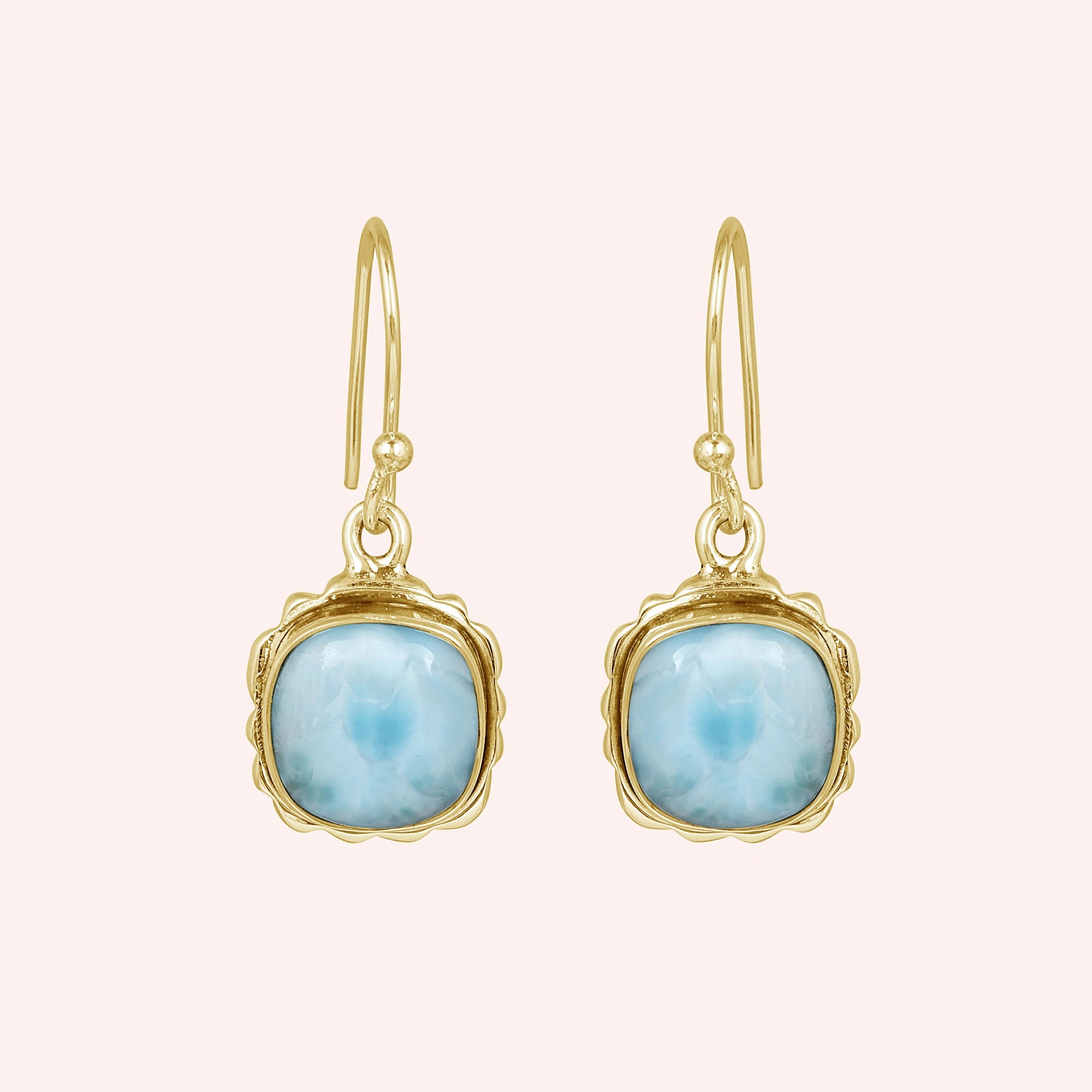 Gold plated sterling silver dangle earrings with cushion-cut larimar stones in a face-on view on a plain pink background