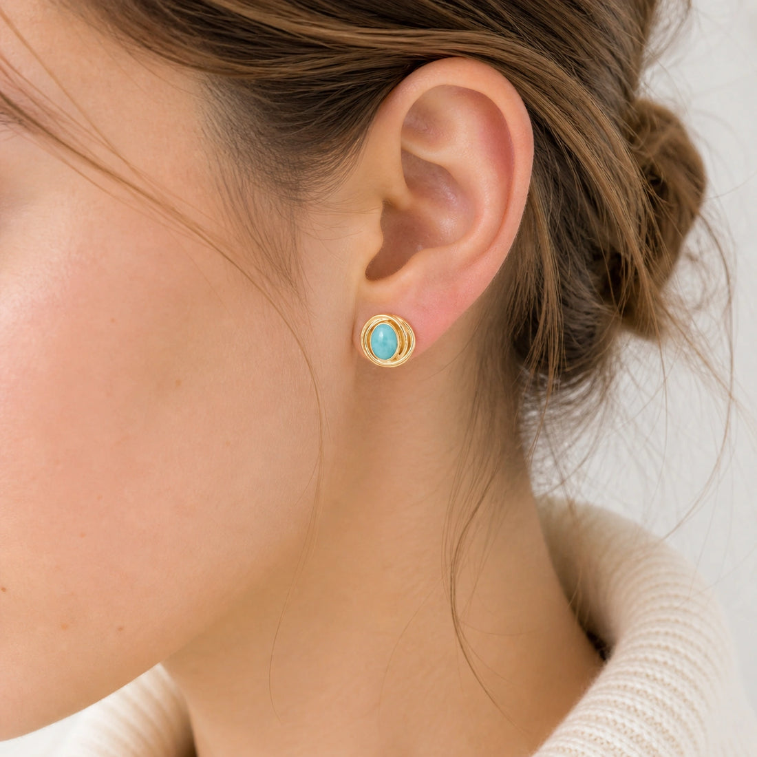 Larimar_earrings_gold_plated_silver_stud_design_with_oval_larimar_stone_shown_at_front_angle_on_soft_fabric_background