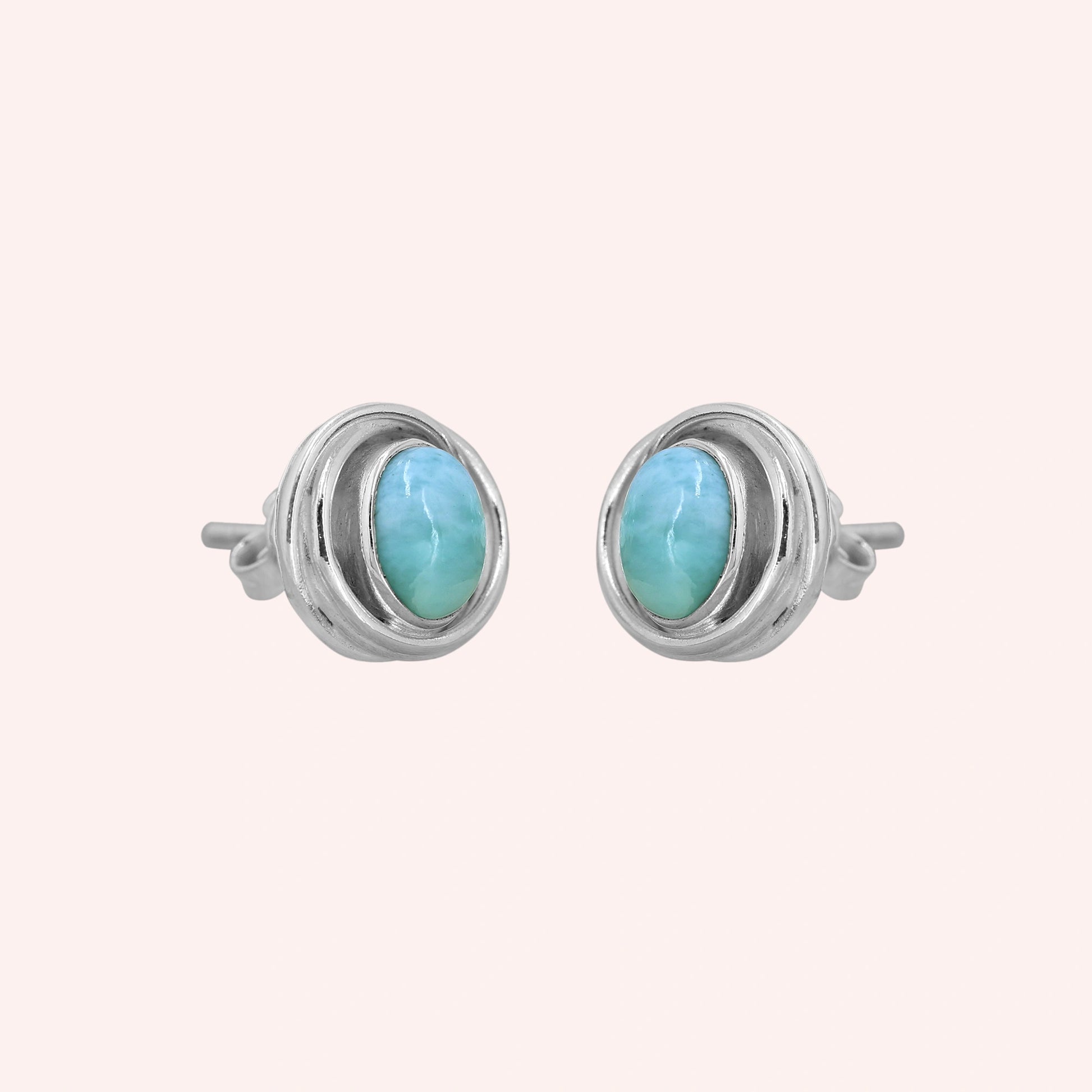 Larimar_earrings_sterling_silver_stud_design_with_oval_larimar_stone_shown_slightly_angled_on_solid_pink_background