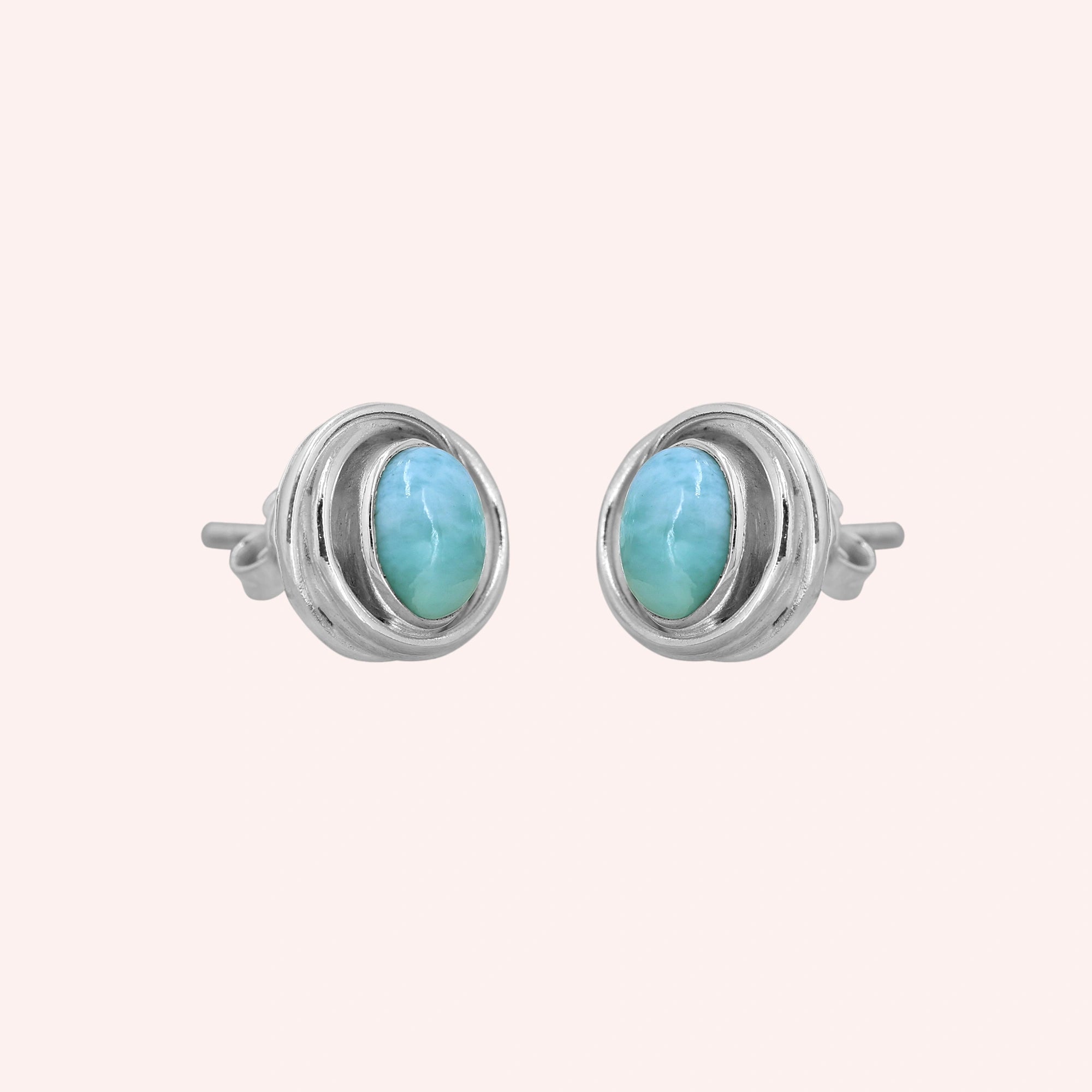 Larimar_earrings_sterling_silver_stud_design_with_oval_larimar_stone_shown_slightly_angled_on_solid_pink_background
