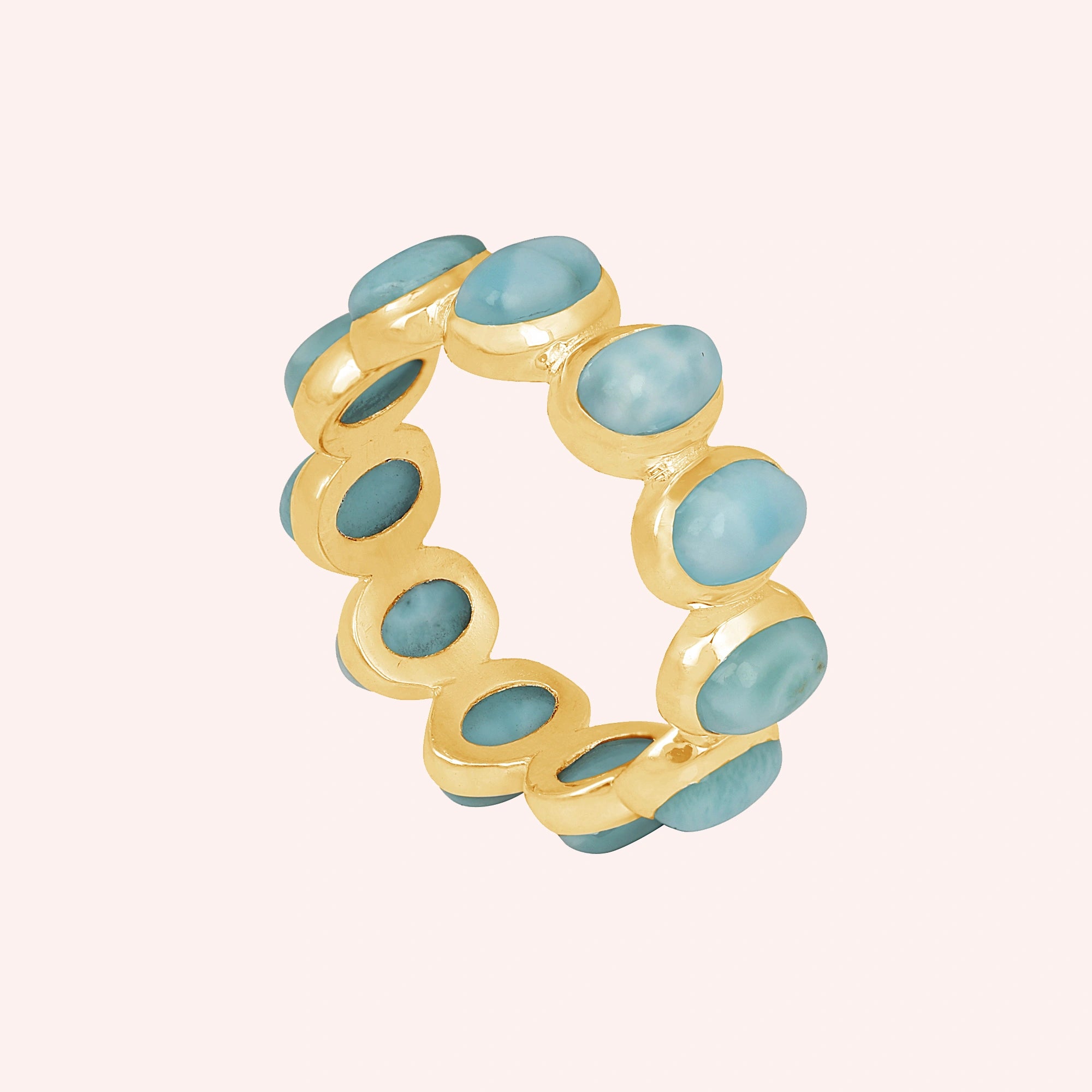 Gold vermeil sterling silver larimar ring eternity band photographed from a slightly elevated angle on a blush pink background