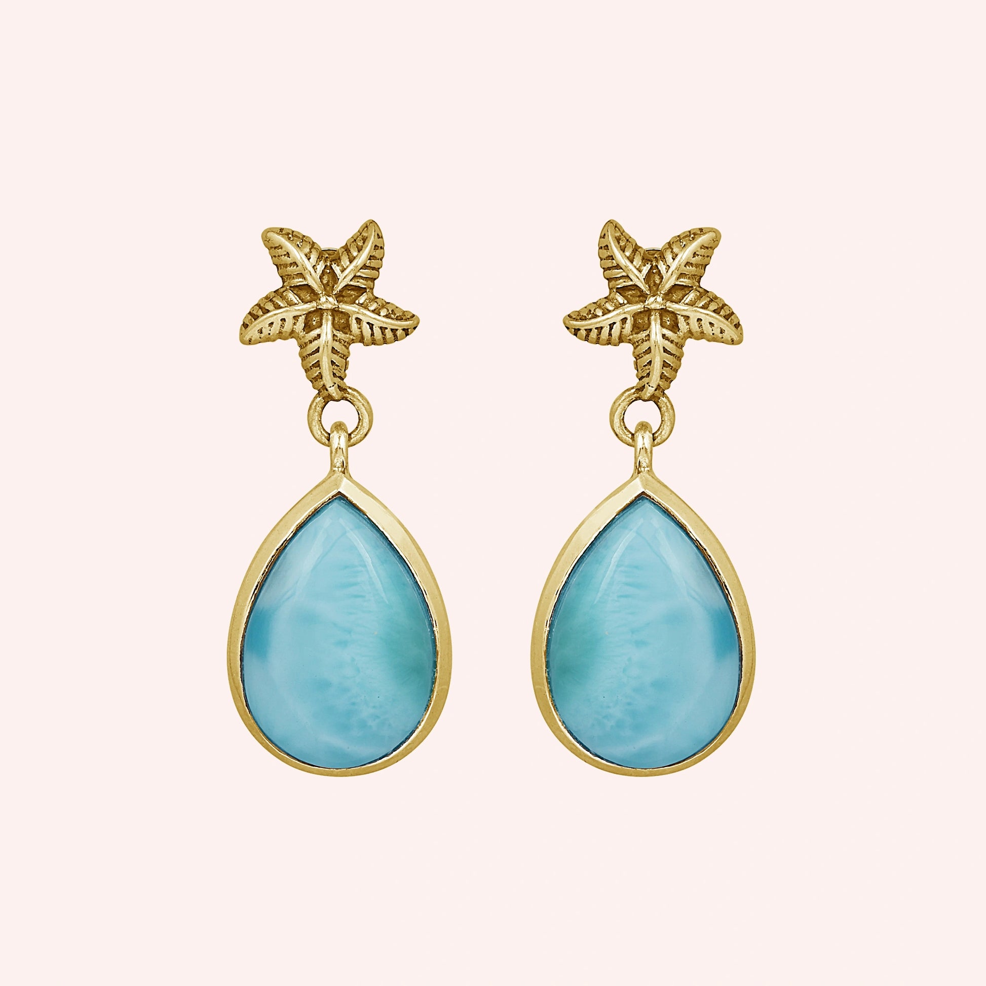 Starfish earrings gold tone larimar teardrop dangles on light pink background from a straight angle view