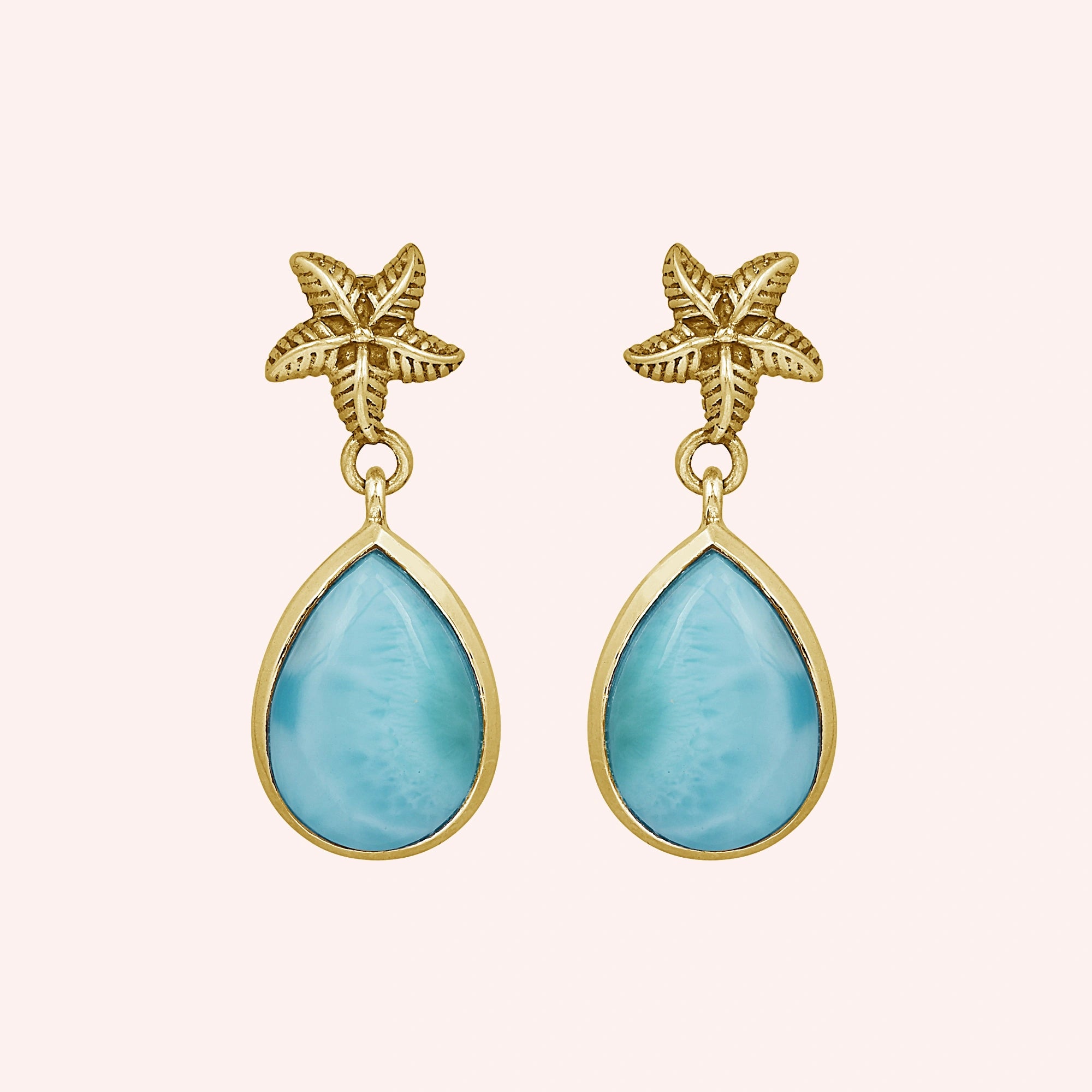 Starfish earrings gold tone larimar teardrop dangles on light pink background from a straight angle view