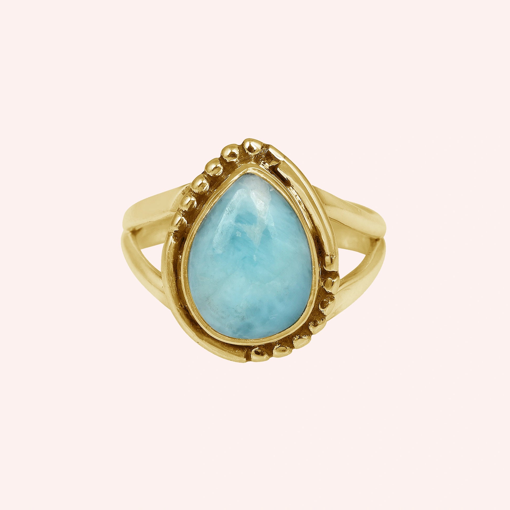 Gold plated silver teardrop ring with teardrop larimar gemstone on light pink background from a straight product angle view