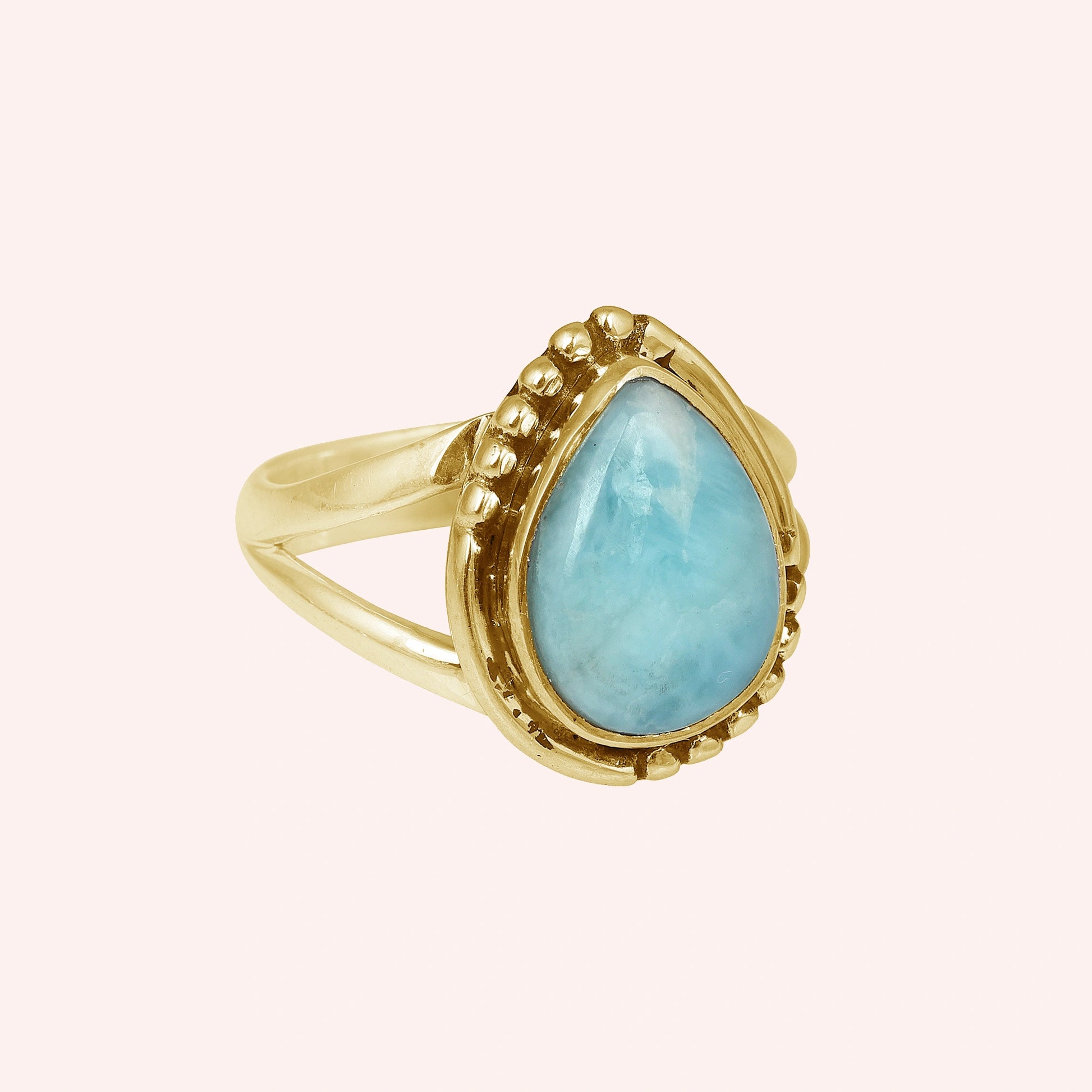 Gold plated silver teardrop ring with teardrop larimar gemstone on light pink background from a straight product angle view