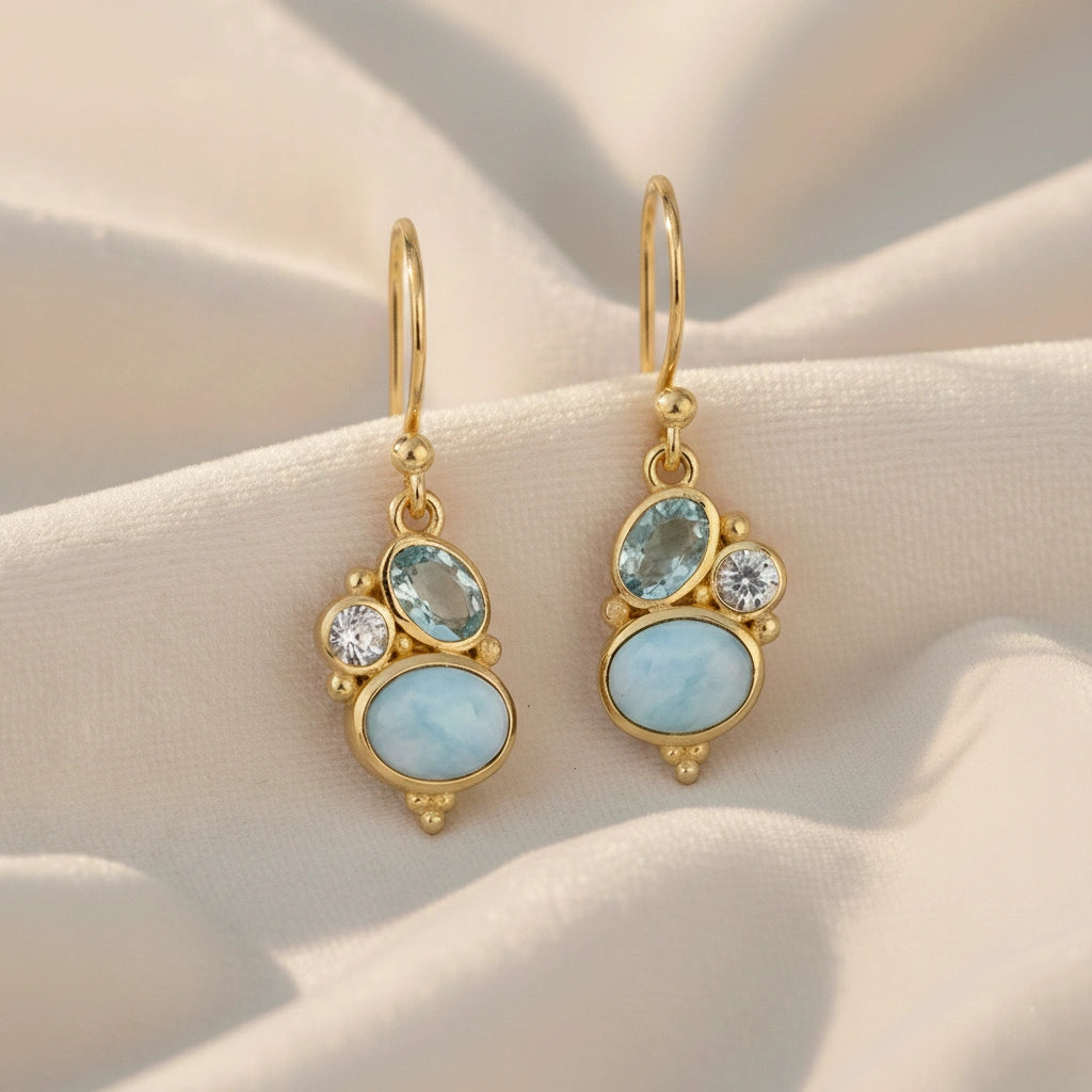 Gold plated boho dangle earrings with a trio gemstones larimar blue topaz moonstone on white draped fabric straight angle view