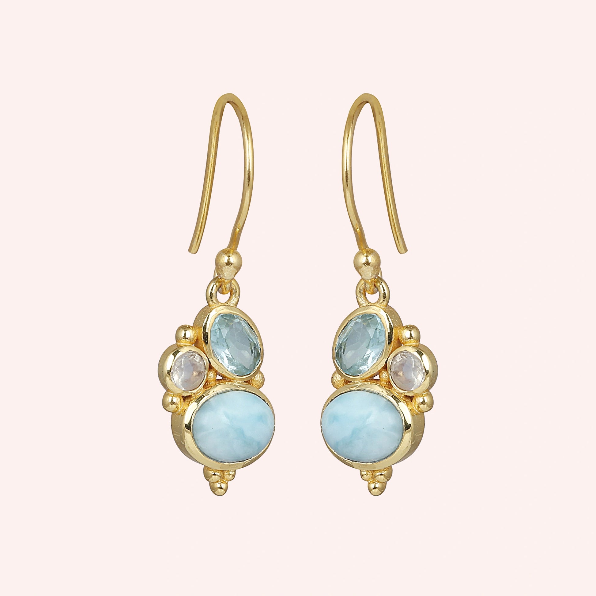 Gold plated boho dangle earrings with a trio gemstones larimar moonstone blue topaz on light pink background slightly angled view
