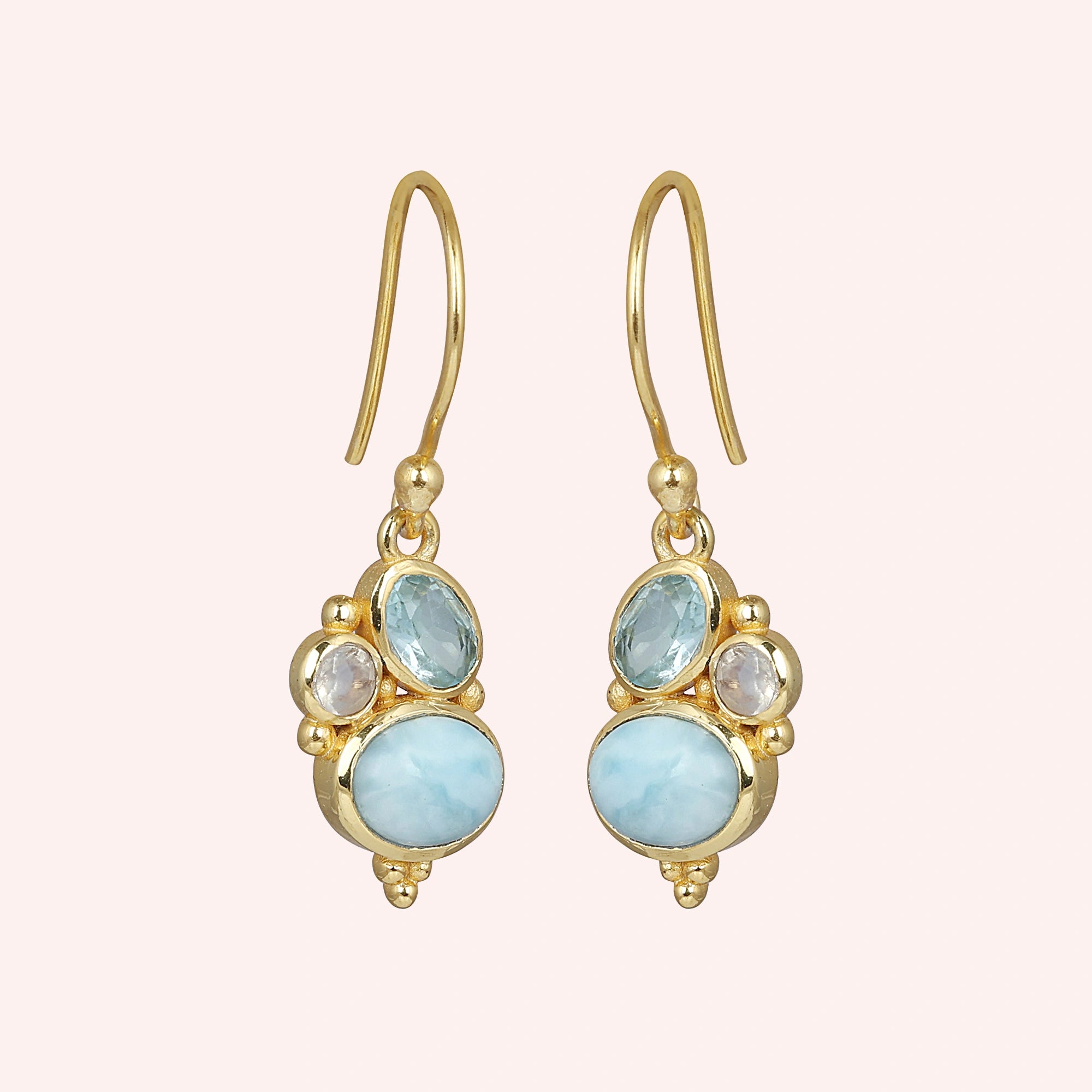 Gold plated boho dangle earrings with a trio gemstones larimar moonstone blue topaz on light pink background slightly angled view