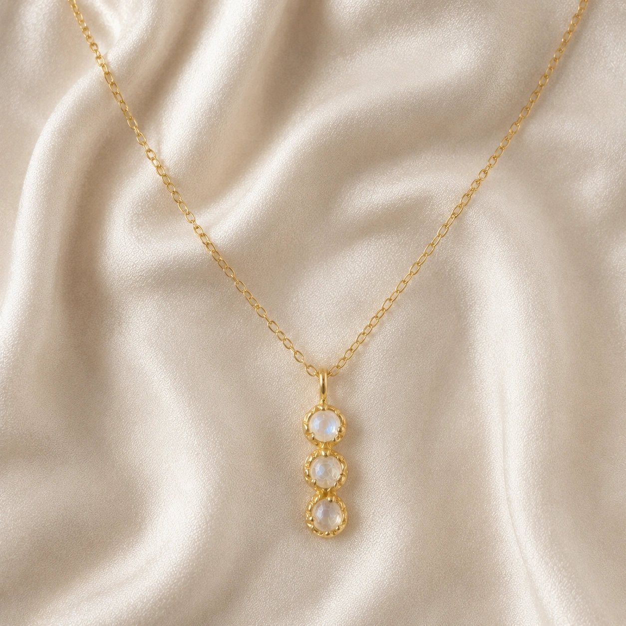 Layering_necklace_in_gold_plated_silver_at_front_angle_featuring_moonstone_drop_on_a_soft_fabric_background