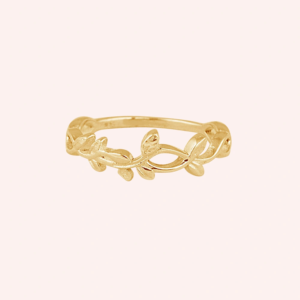 Leaf_ring_in_gold_plated_silver_with_a_floral_design_at_front_angle_on_solid_pink_background