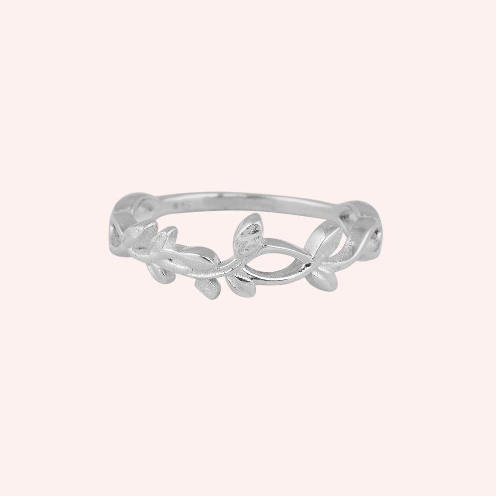 Leaf_ring_in_sterling_silver_with_a_floral_design_at_front_angle_on_solid_pink_background