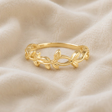Leaf_ring_in_gold_plated_silver_with_a_floral_design_at_front_angle_on_soft_fabric_background