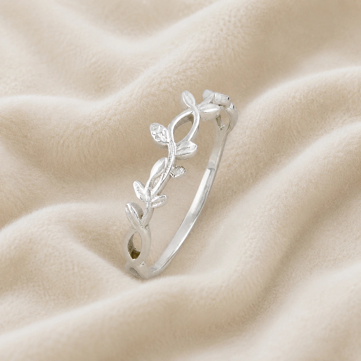 Leaf_ring_in_sterling_silver_with_a_floral_design_at_slight_angle_on_soft_fabric_background