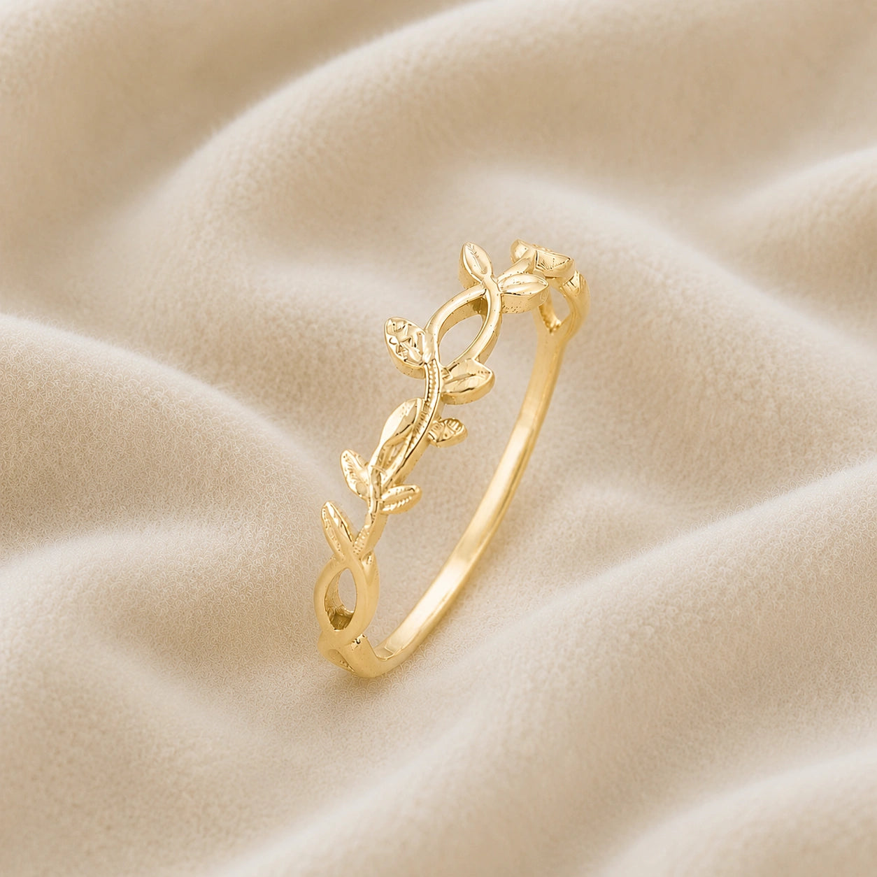 Leaf_ring_in_gold_plated_silver_with_a_floral_design_at_slight_angle_on_soft_fabric_background