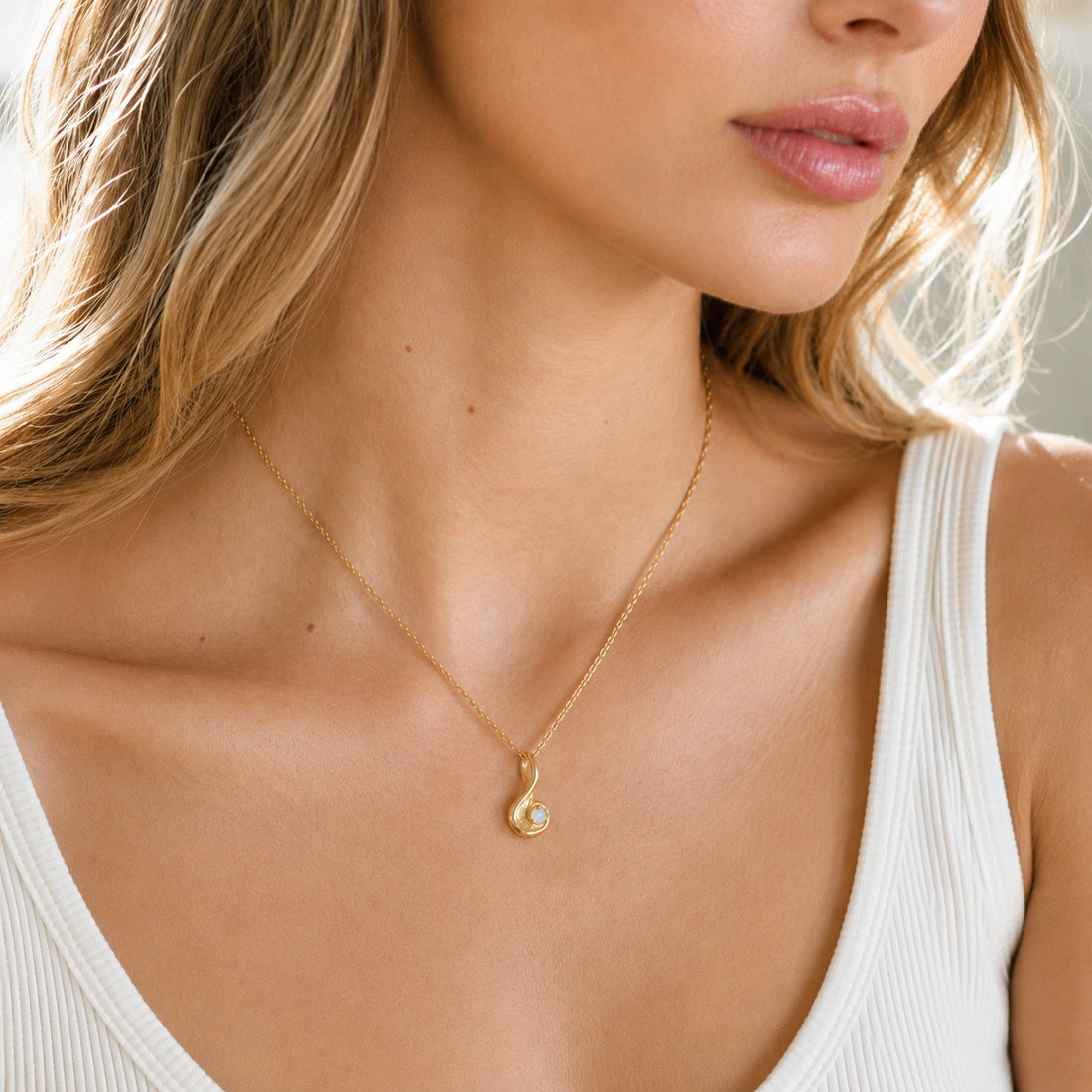 Locket_necklace_with_gold_plated_silver_teardrop_pendant_and_moonstone_at_front_angle_on_soft_fabric_background