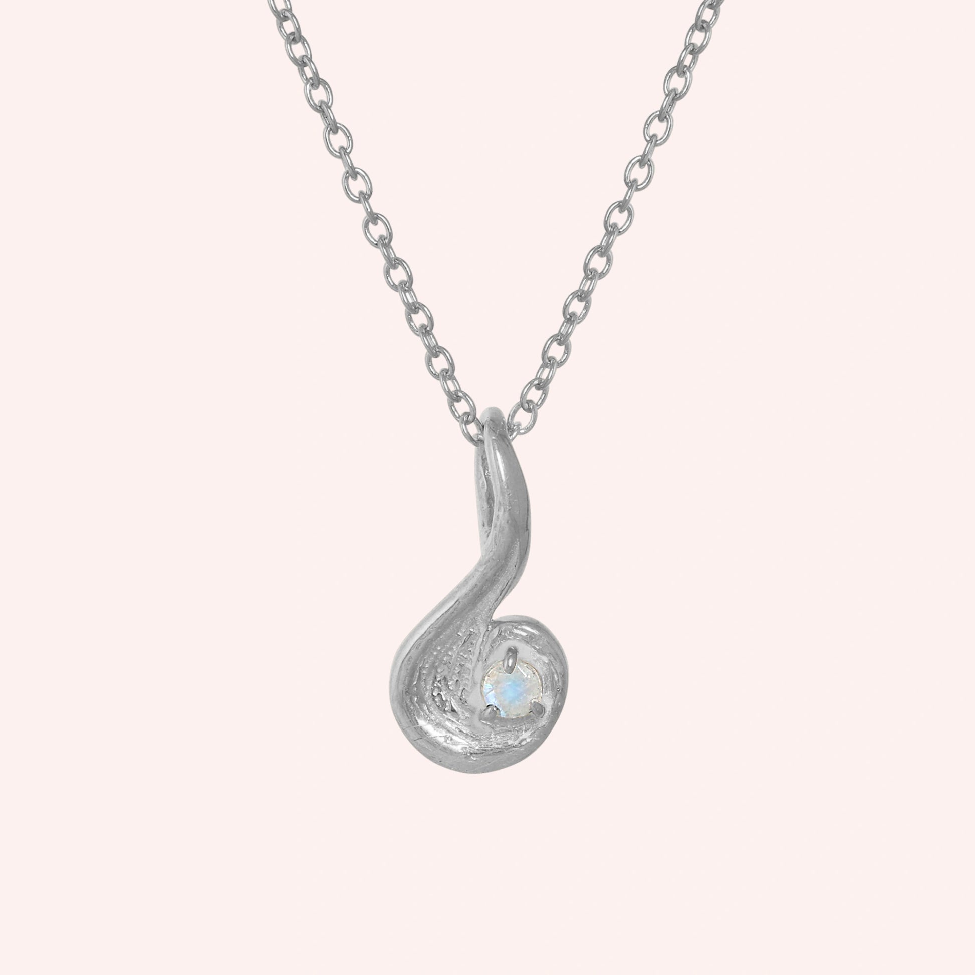 Locket_necklace_with_sterling_silver_teardrop_pendant_and_moonstone_at_front_angle_on_solid_pink_background
