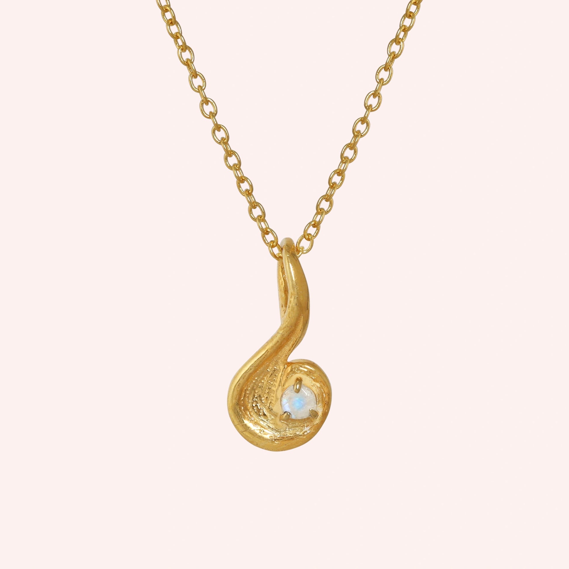 Locket_necklace_with_gold_plated_silver_teardrop_pendant_and_moonstone_at_front_angle_on_solid_pink_background