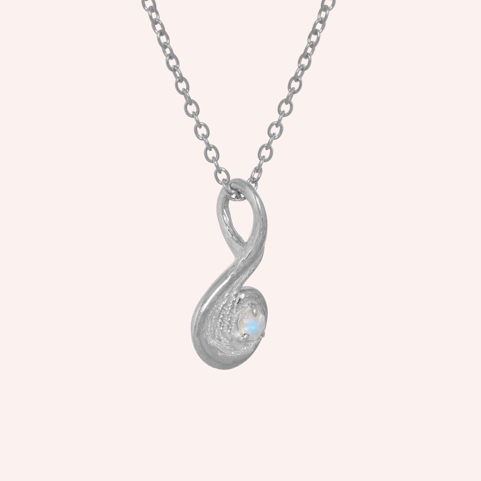 Locket_necklace_with_sterling_silver_teardrop_pendant_and_moonstone_at_slightly_angled_on_solid_pink_background