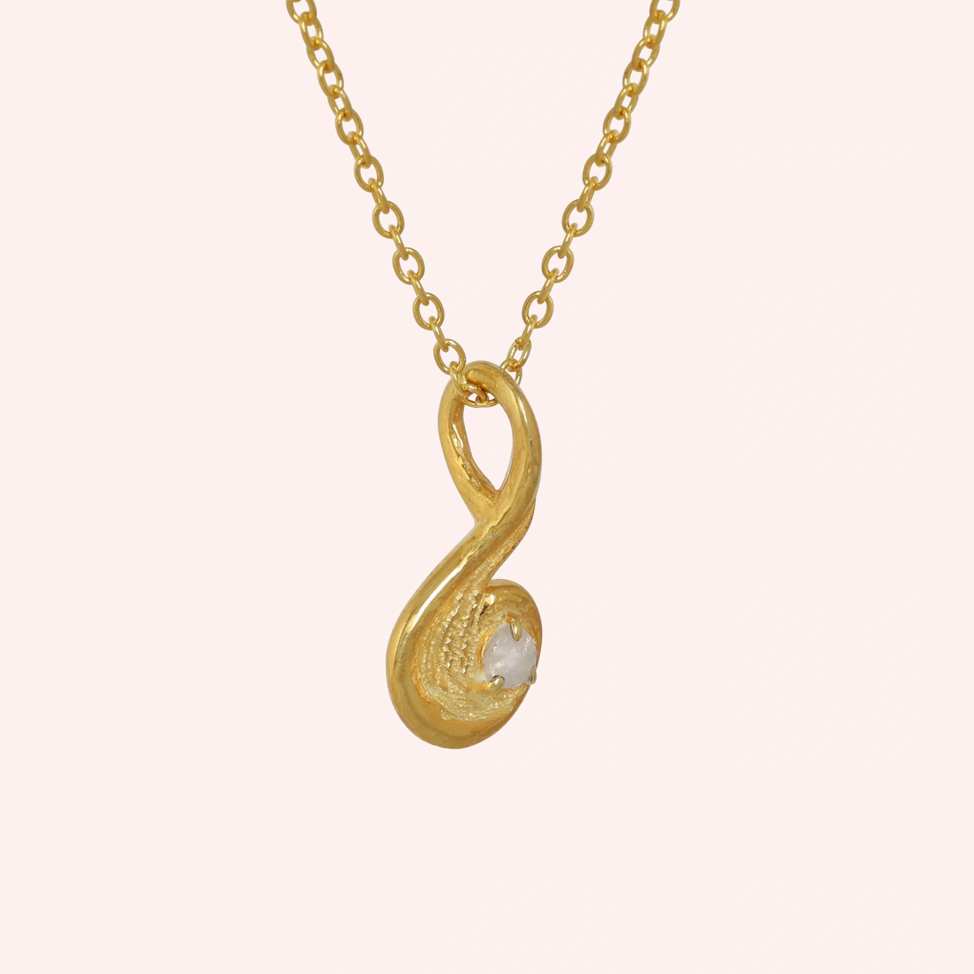 Locket_necklace_with_gold_plated_silver_teardrop_pendant_and_moonstone_at_slightly_angled_on_solid_pink_background