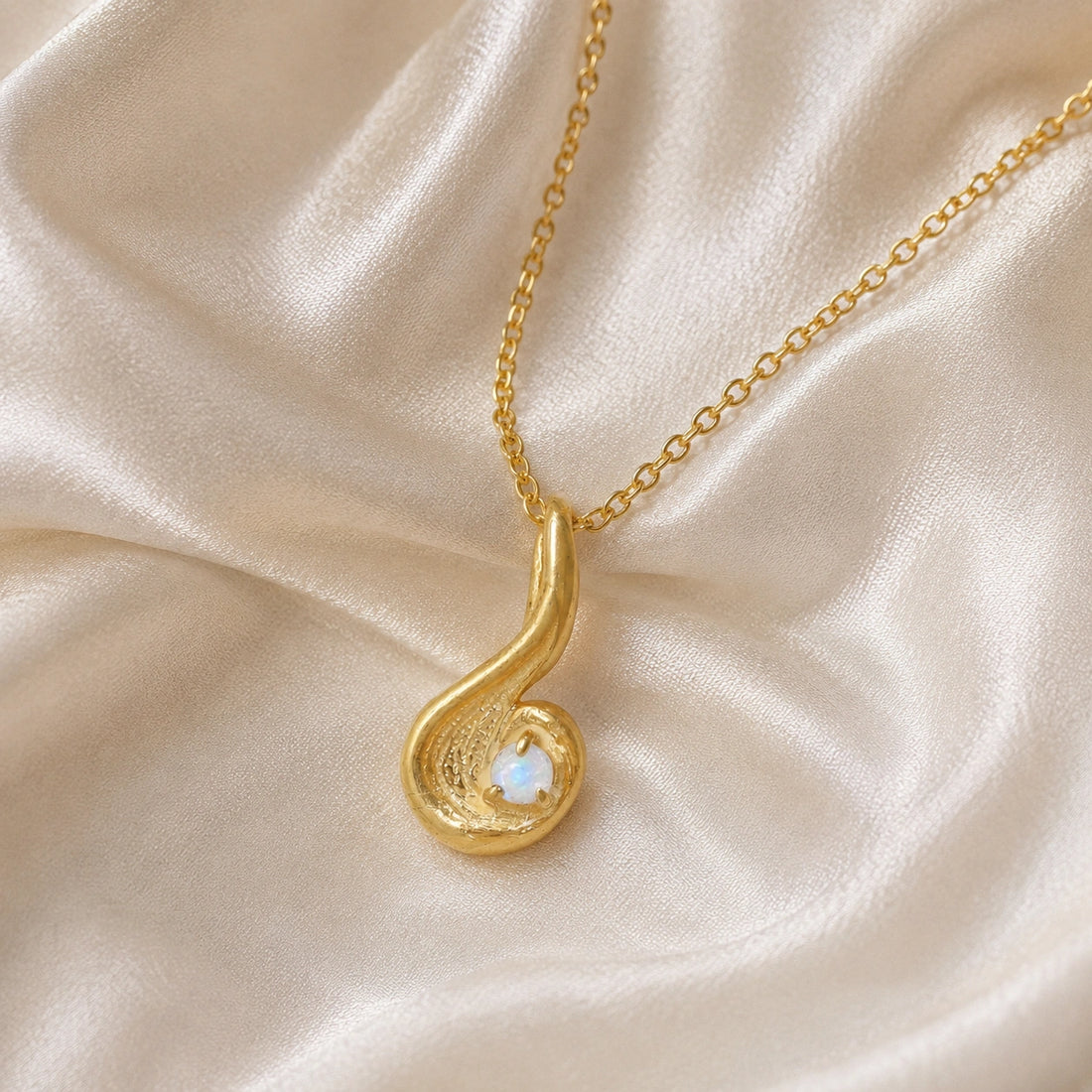 Locket_necklace_with_gold_plated_silver_teardrop_pendant_and_moonstone_at_front_angle_on_soft_fabric_background