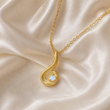 Locket_necklace_with_gold_plated_silver_teardrop_pendant_and_moonstone_at_front_angle_on_soft_fabric_background