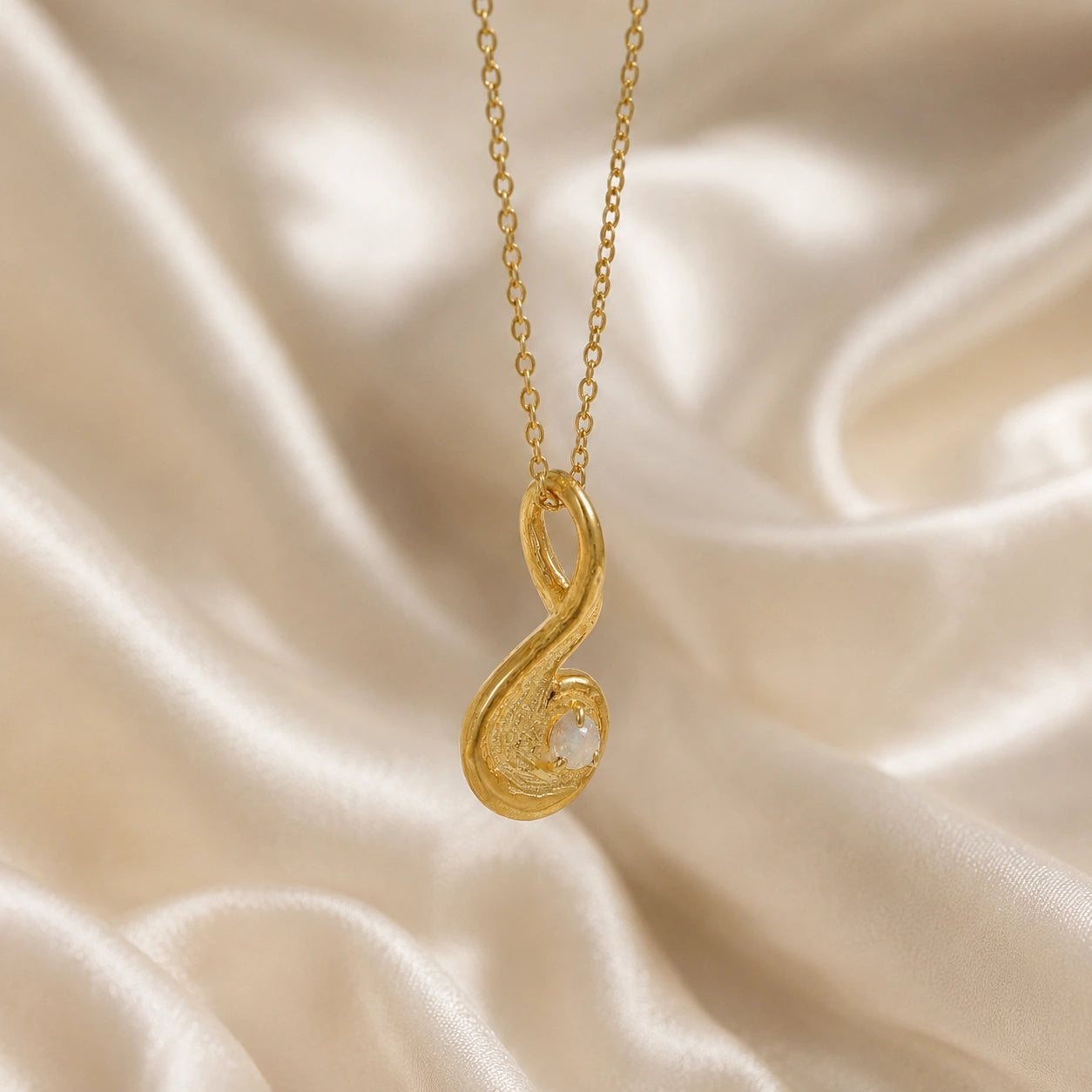Locket_necklace_with_gold_plated_silver_teardrop_pendant_and_moonstone_at_slightly_angled_on_soft_fabric_background