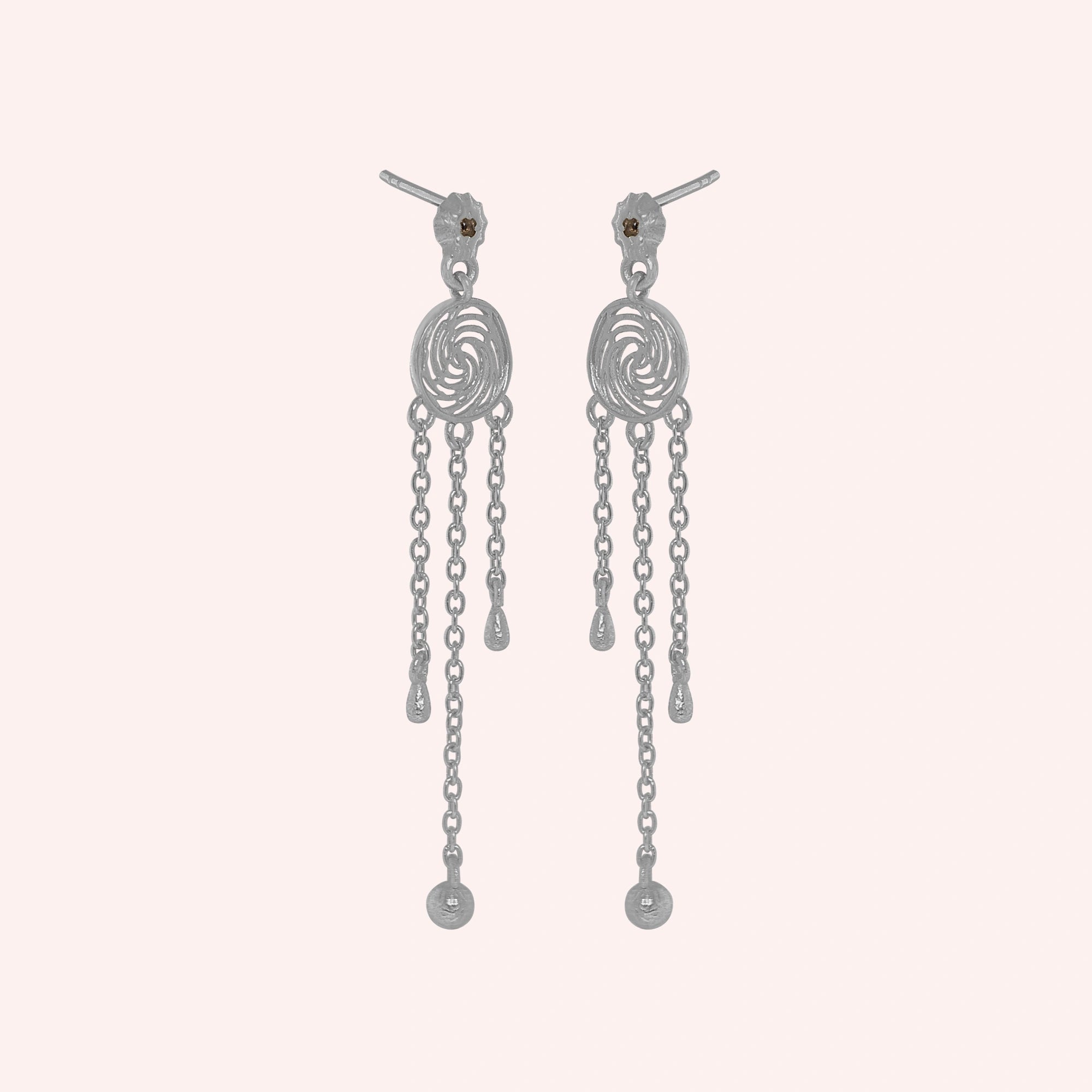 Long_chain_earrings_in_sterling_silver_featuring_smoky_quartz_stone_at_slight_angle_on_solid_pink_background