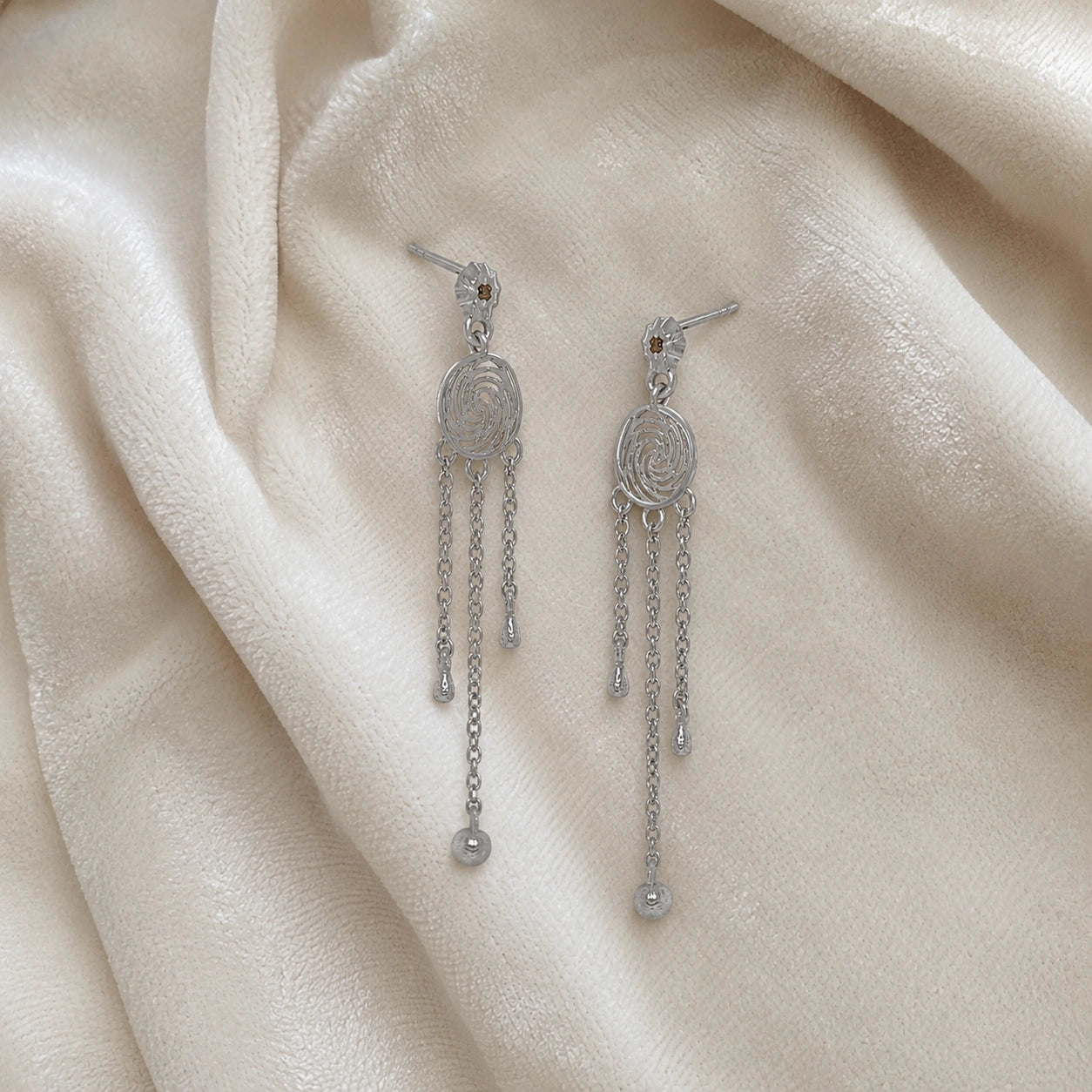 Long_chain_earrings_in_sterling_silver_featuring_smoky_quartz_stone_at_slight_angle_on_soft_fabric_background