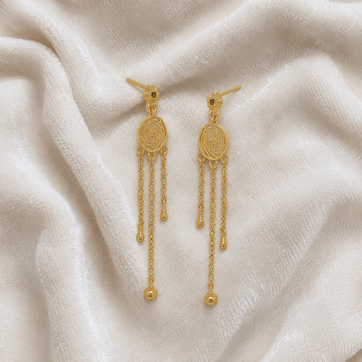 Long_chain_earrings_in_gold_plated_silver_featuring_smoky_quartz_stone_at_slight_angle_on_soft_fabric_background