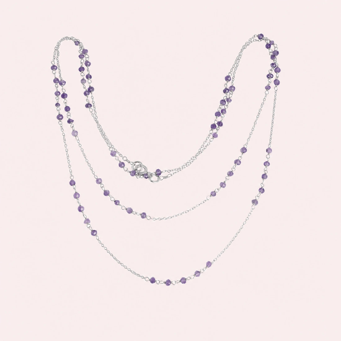 Long_chain_necklace_in_gold_plated_silver_with_amethyst_beads_at_front_angle_view_on_solid_pink_background