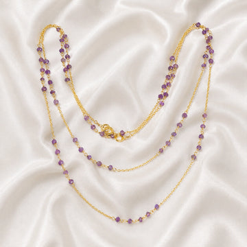 Long_chain_necklace_in_gold_plated_silver_with_amethyst_beads_at_front_angle_view_on_soft_fabric_background