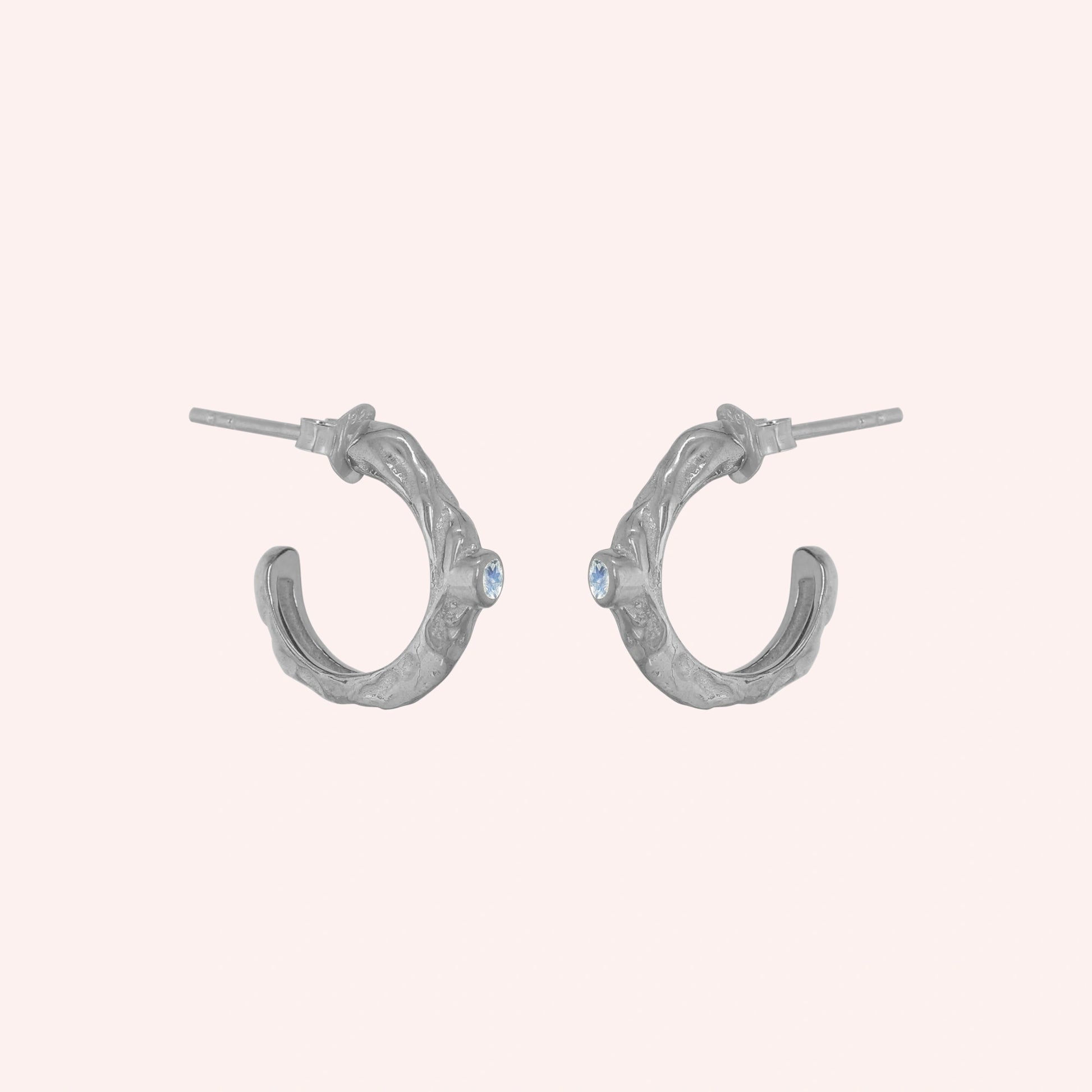 Mini_hoop_earrings_sterling_silver_hoop_design_with_moonstone_in_side_angle_view_on_solid_pink_background