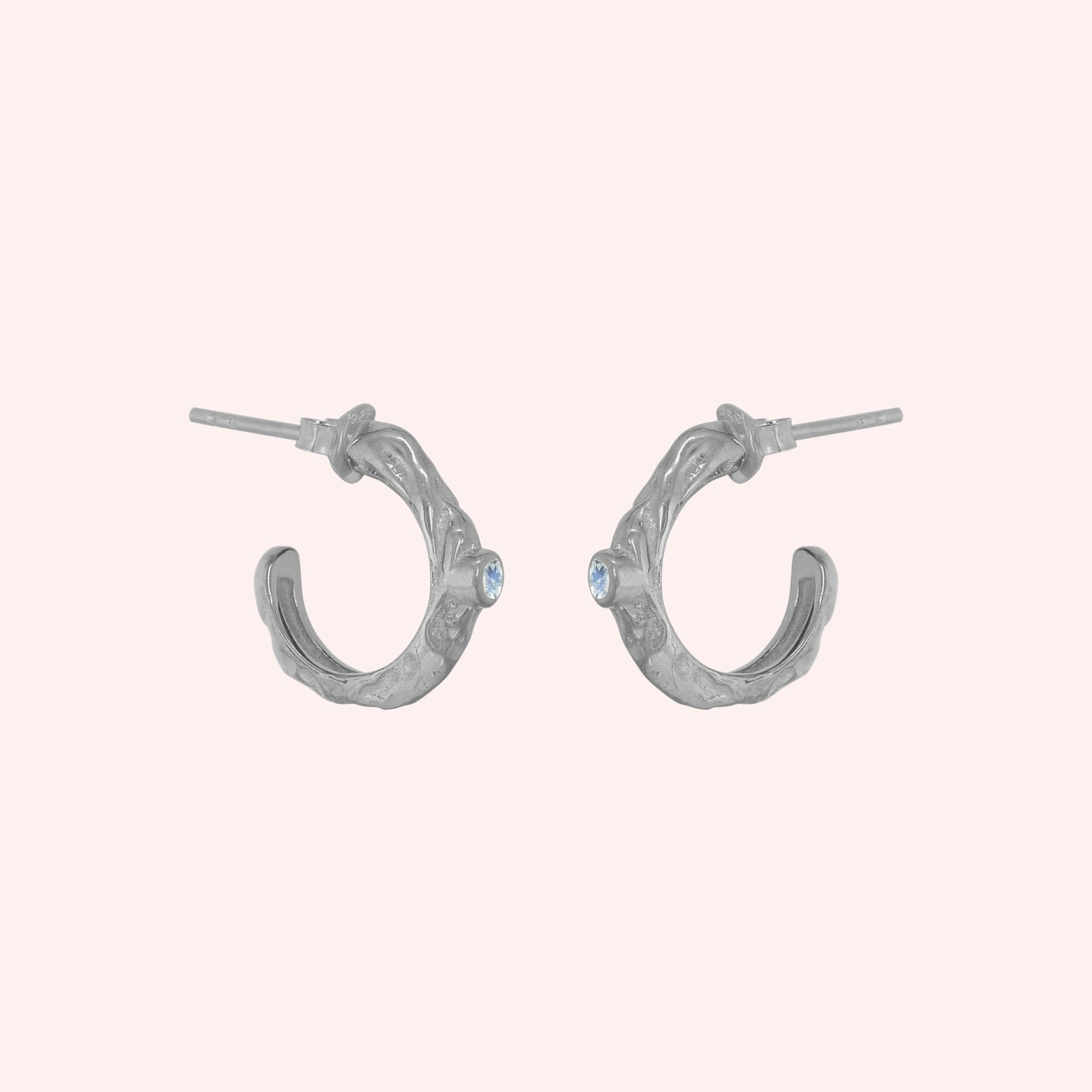 Mini_hoop_earrings_sterling_silver_hoop_design_with_moonstone_in_side_angle_view_on_solid_pink_background