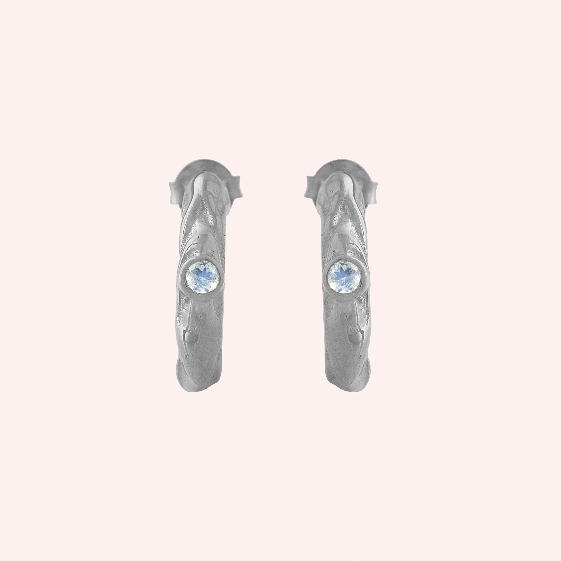 Mini_hoop_earrings_sterling_silver_hoop_design_with_moonstone_in_front_angle_view_on_solid-pink_background