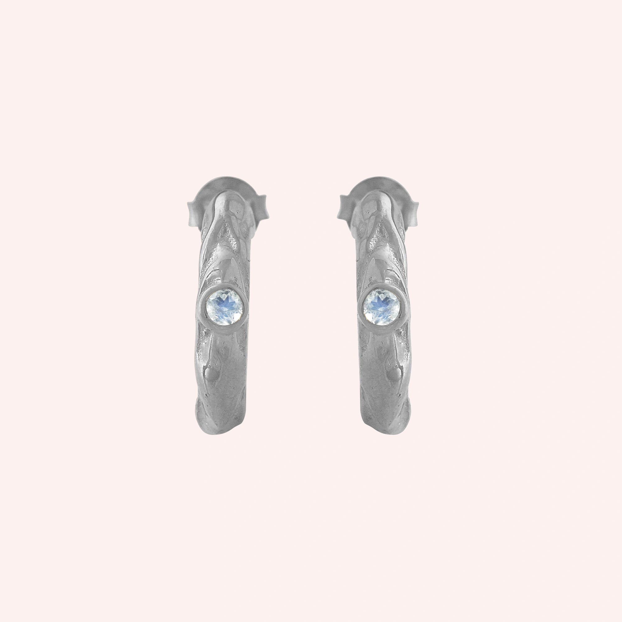 Mini_hoop_earrings_sterling_silver_hoop_design_with_moonstone_in_front_angle_view_on_solid-pink_background