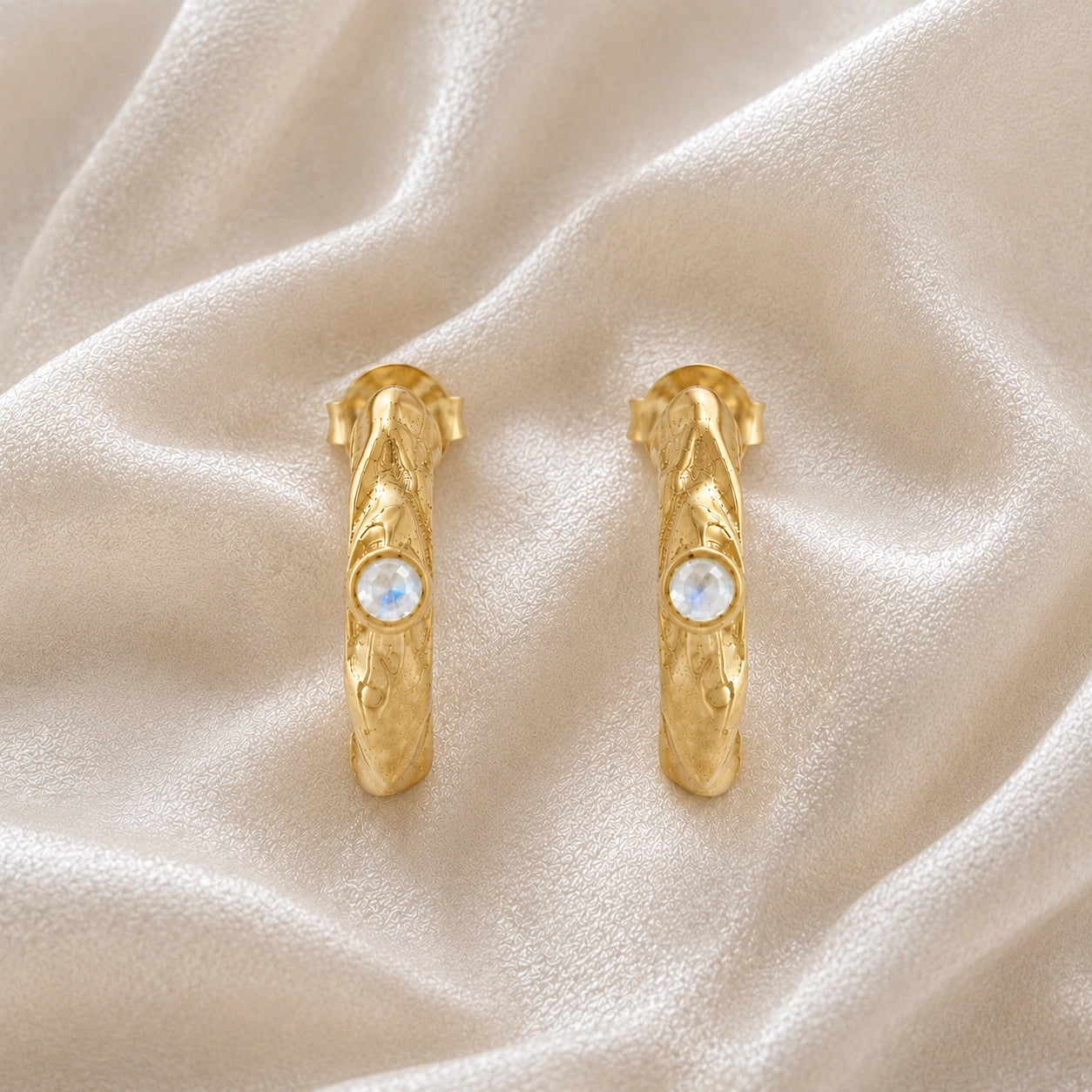 Mini_hoop_earrings_gold_plated_silver_hoop_design_with_moonstone_in_front_angle_view_on_soft_fabric_background