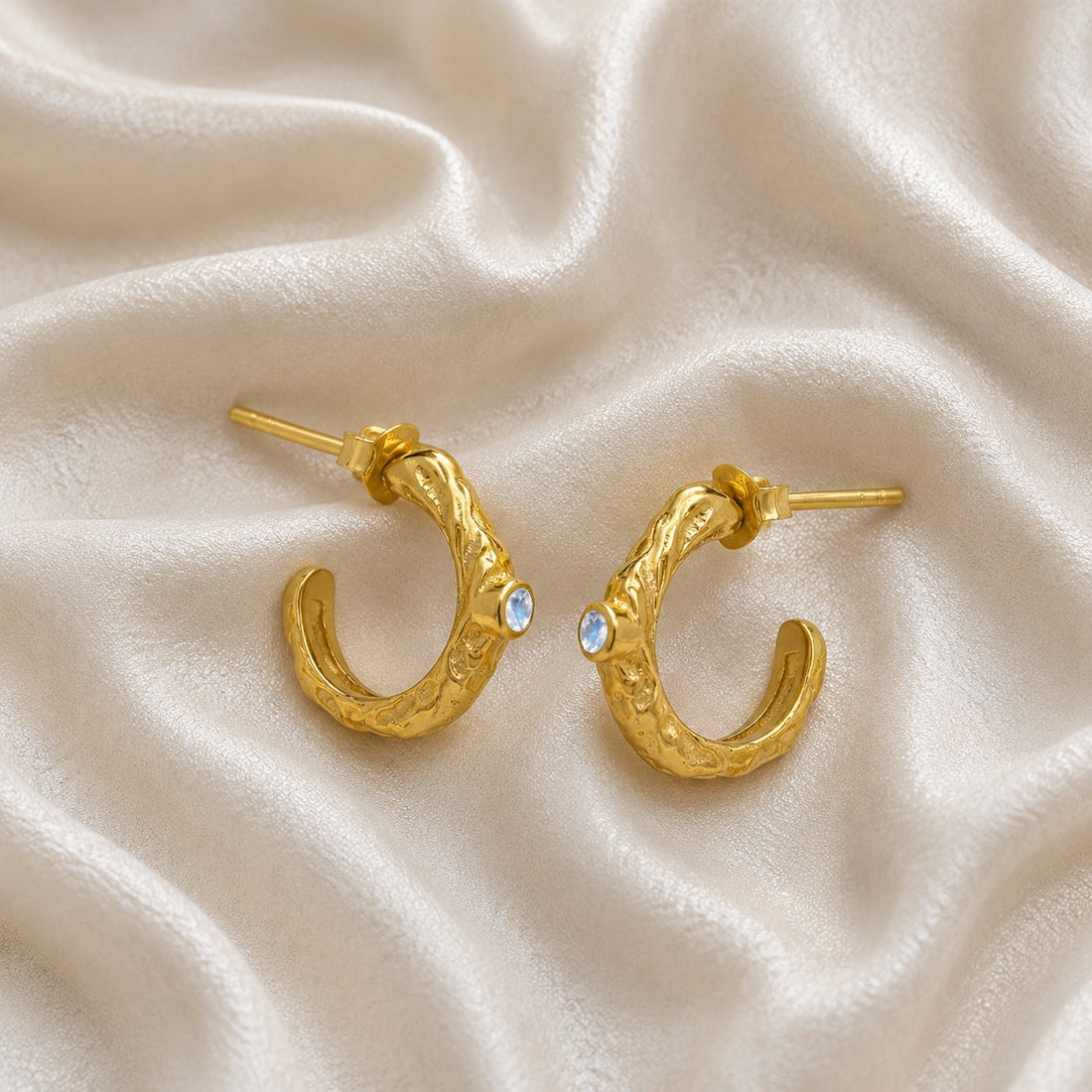 Mini_hoop_earrings_gold_plated_silver_hoop_design_with_moonstone_in_side_angle_view_on_soft_fabric_background
