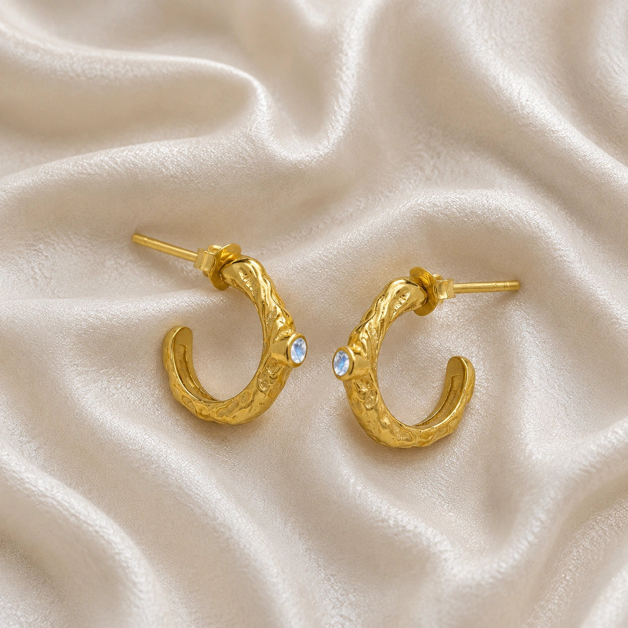 Mini_hoop_earrings_gold_plated_silver_hoop_design_with_moonstone_in_side_angle_view_on_soft_fabric_background