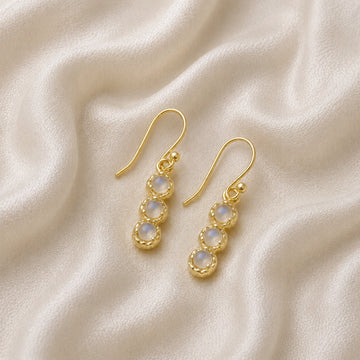 Minimal_earrings_in_gold_plated_silver_at_slightly_angled_featuring_moonstone_drops_on_a_soft_fabric_background