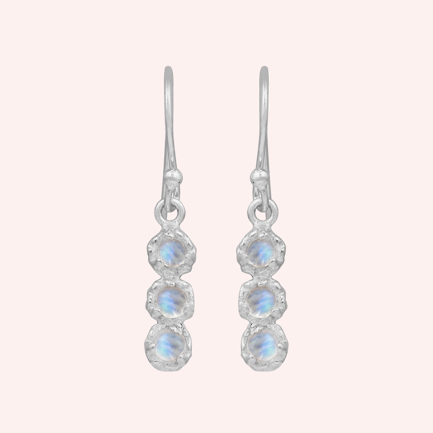Minimal_earrings_in_sterling_silver_at_front_angle_featuring_moonstone_drops_on_a_solid_pink_background