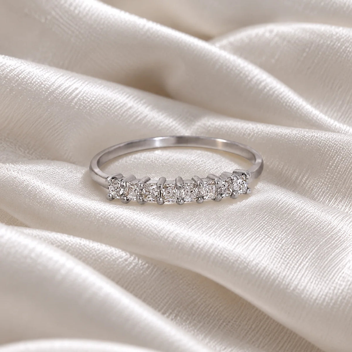 Minimal_ring_in_sterling_silver_with_square_cut_CZ_stones_at_front_angle_view_on_soft_fabric_background