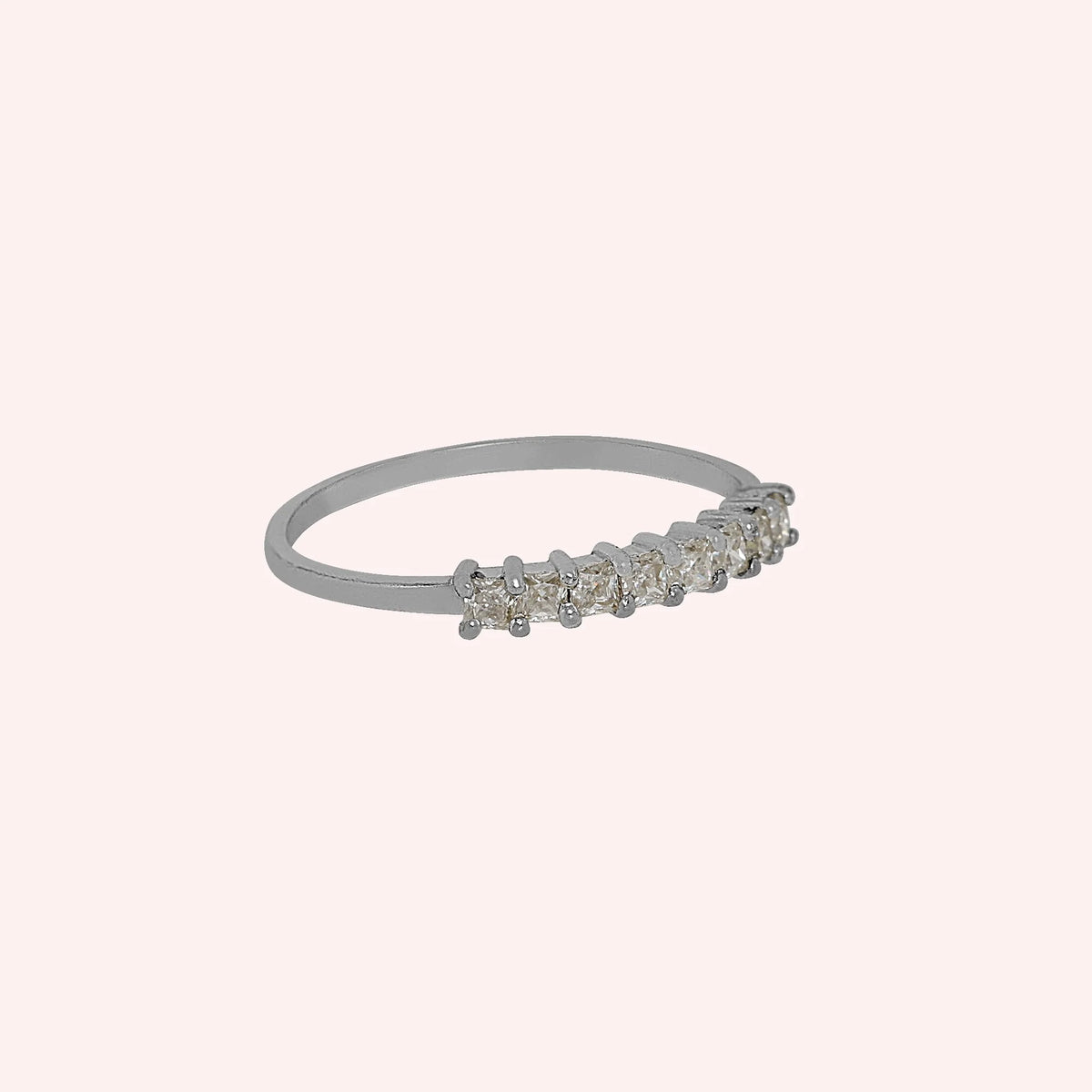Minimal_ring_in_sterling_silver_with_square_cut_CZ_stones_at_side_angle_view_on_solid_pink_background