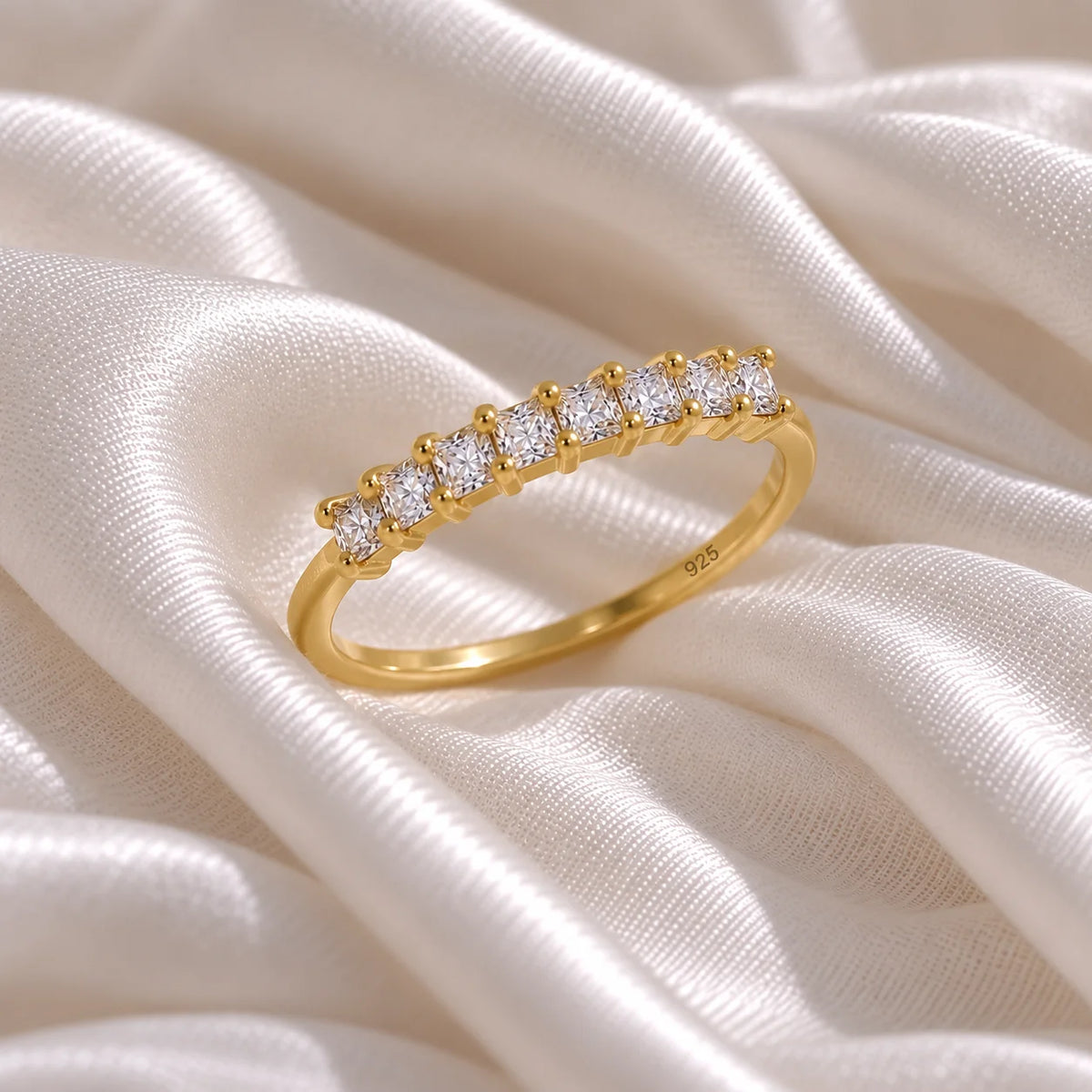 Minimal_ring_in_gold_plated_silver_with_square_cut_CZ_stones_at_side_angle_view_on_soft_fabric_background