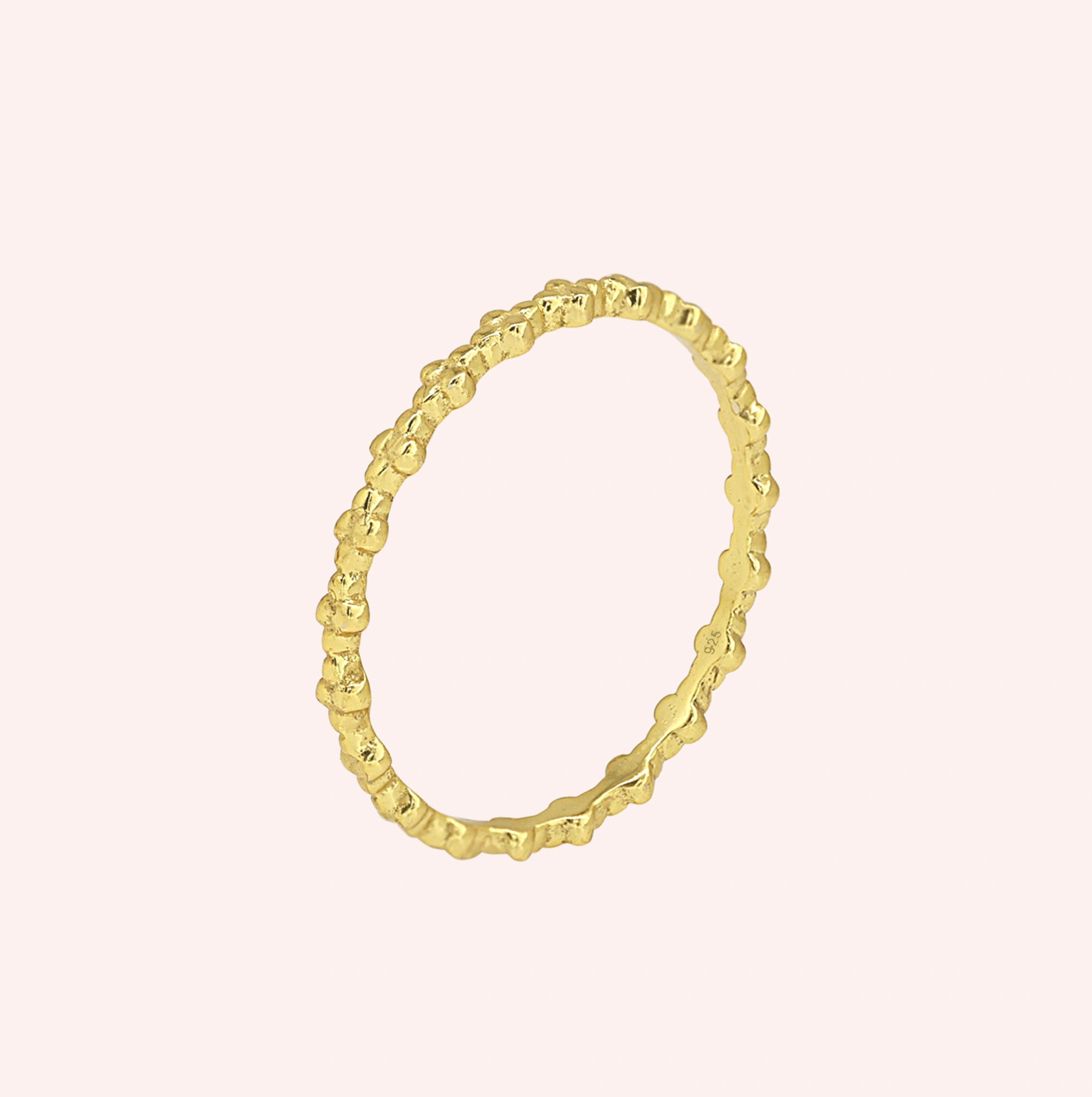 Minimal_ring_in_gold_plated_silver_at_slight_angle_on_solid_pink_background