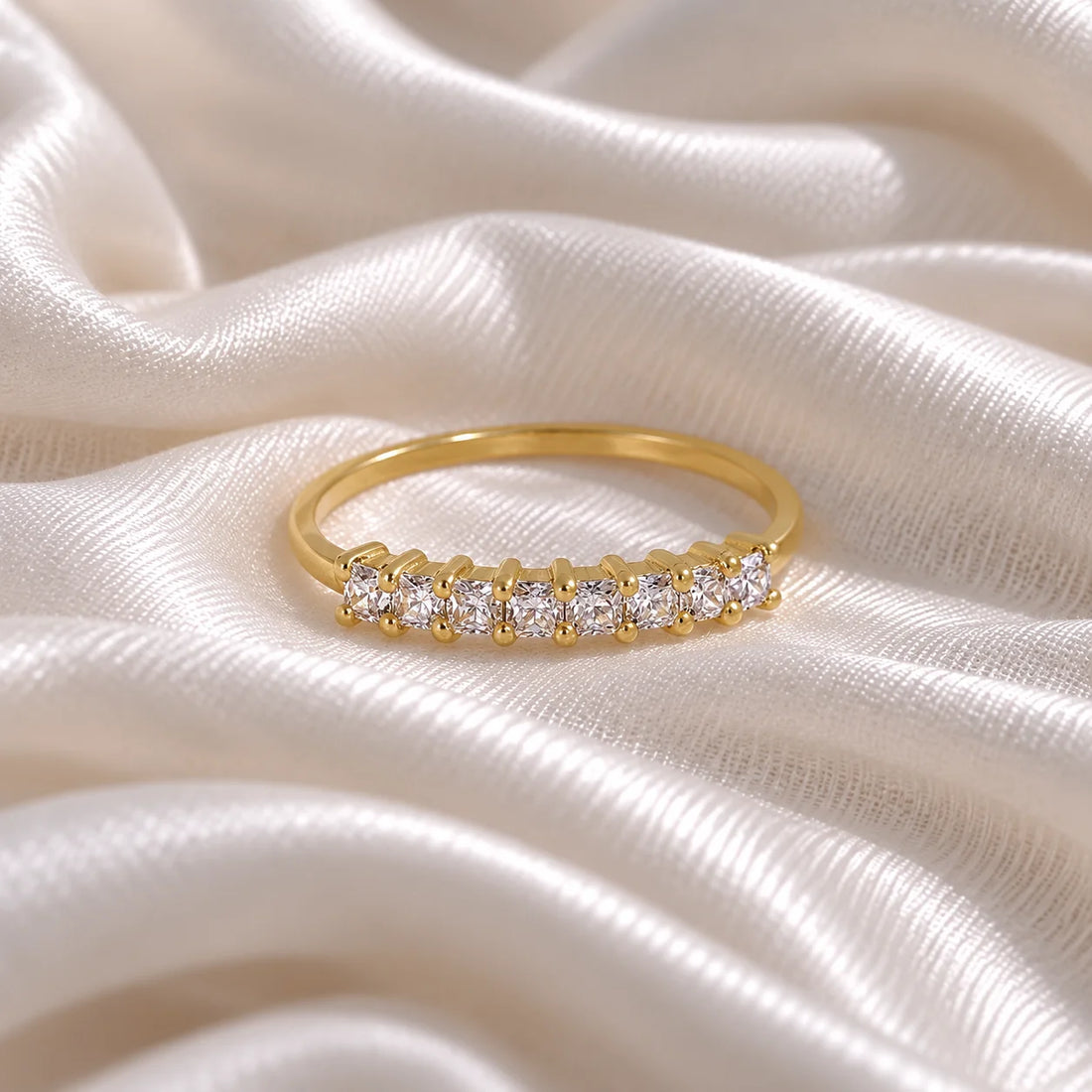 Minimal_ring_in_gold_plated_silver_with_square_cut_CZ_stones_at_front_angle_view_on_soft_fabric_background