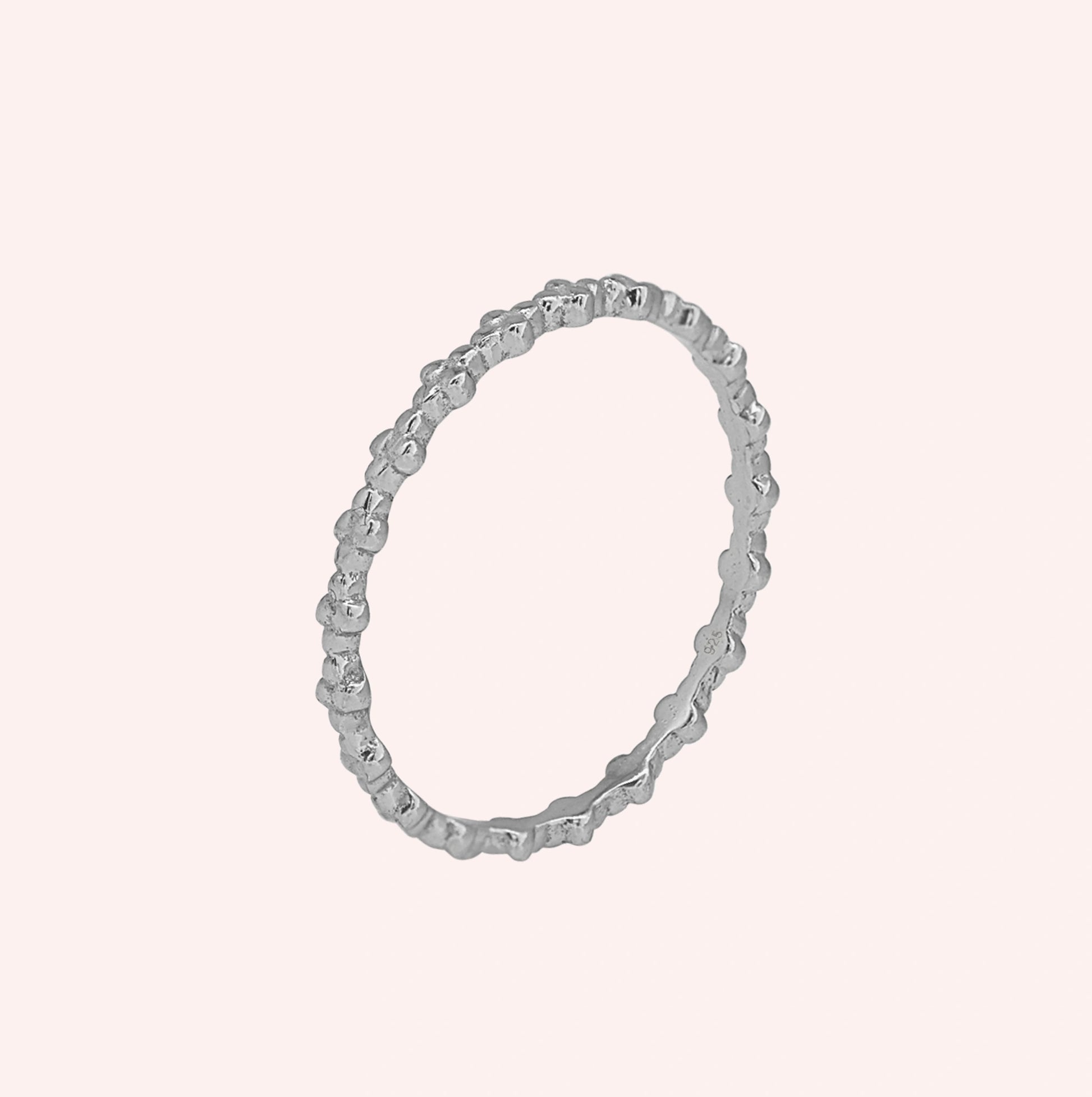 Minimal_ring_in_sterling_silver_at_slight_angle_on_solid_pink_background
