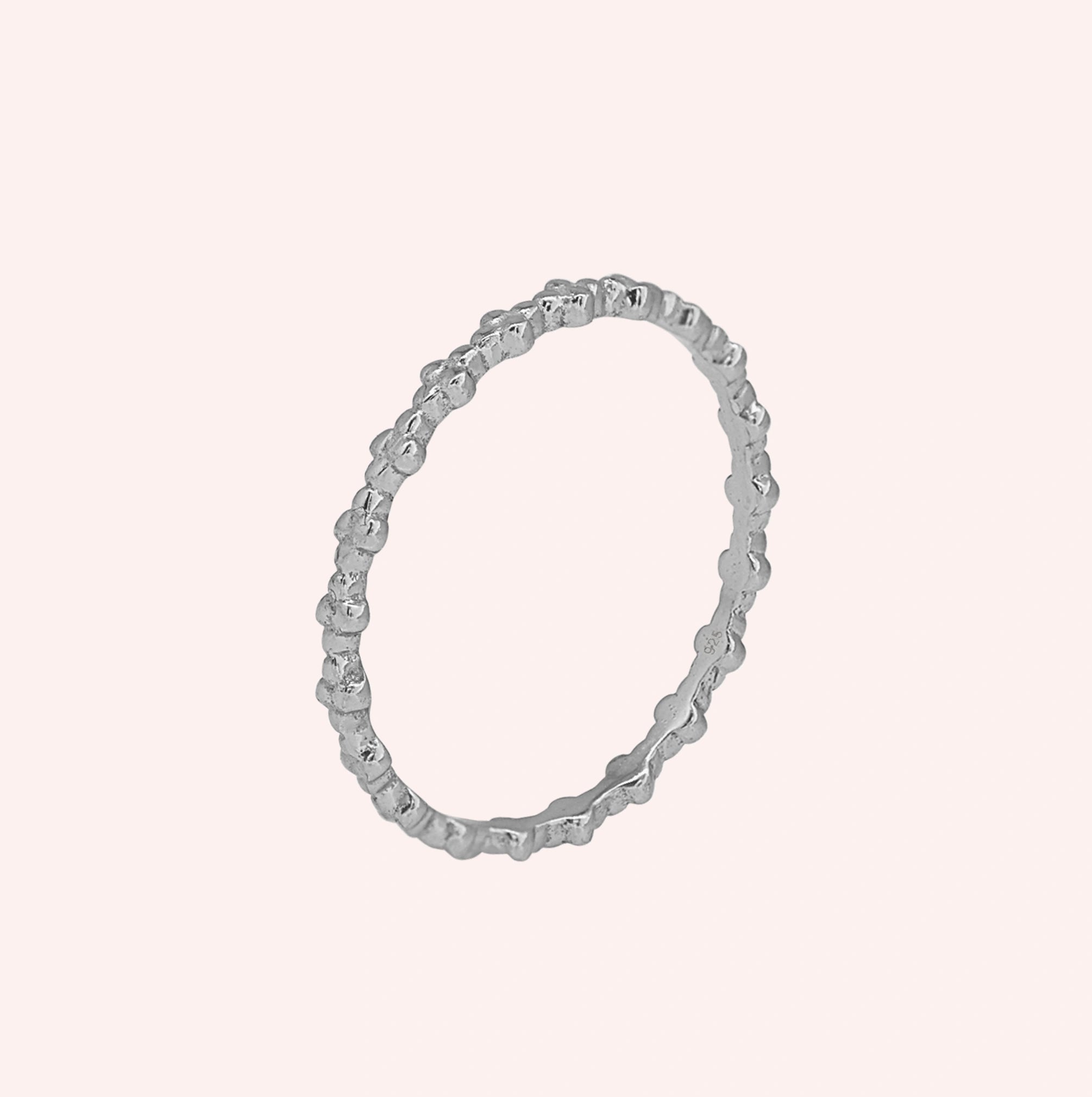 Minimal_ring_in_sterling_silver_at_slight_angle_on_solid_pink_background