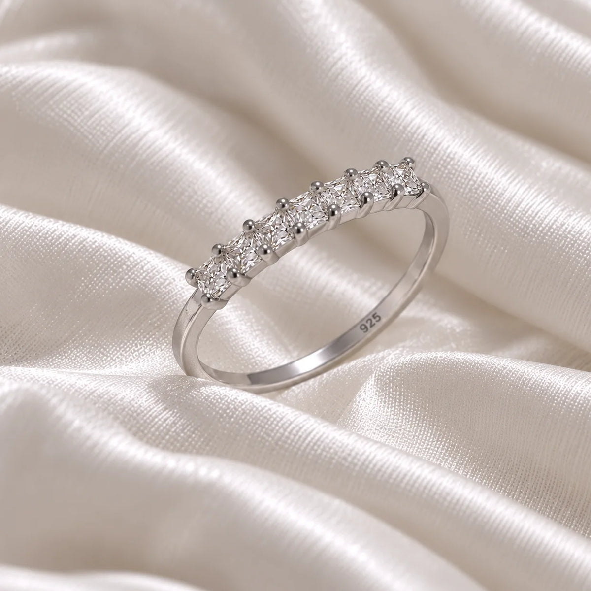 Minimal_ring_in_sterling_silver_with_square_cut_CZ_stones_at_side_angle_view_on_soft_fabric_background