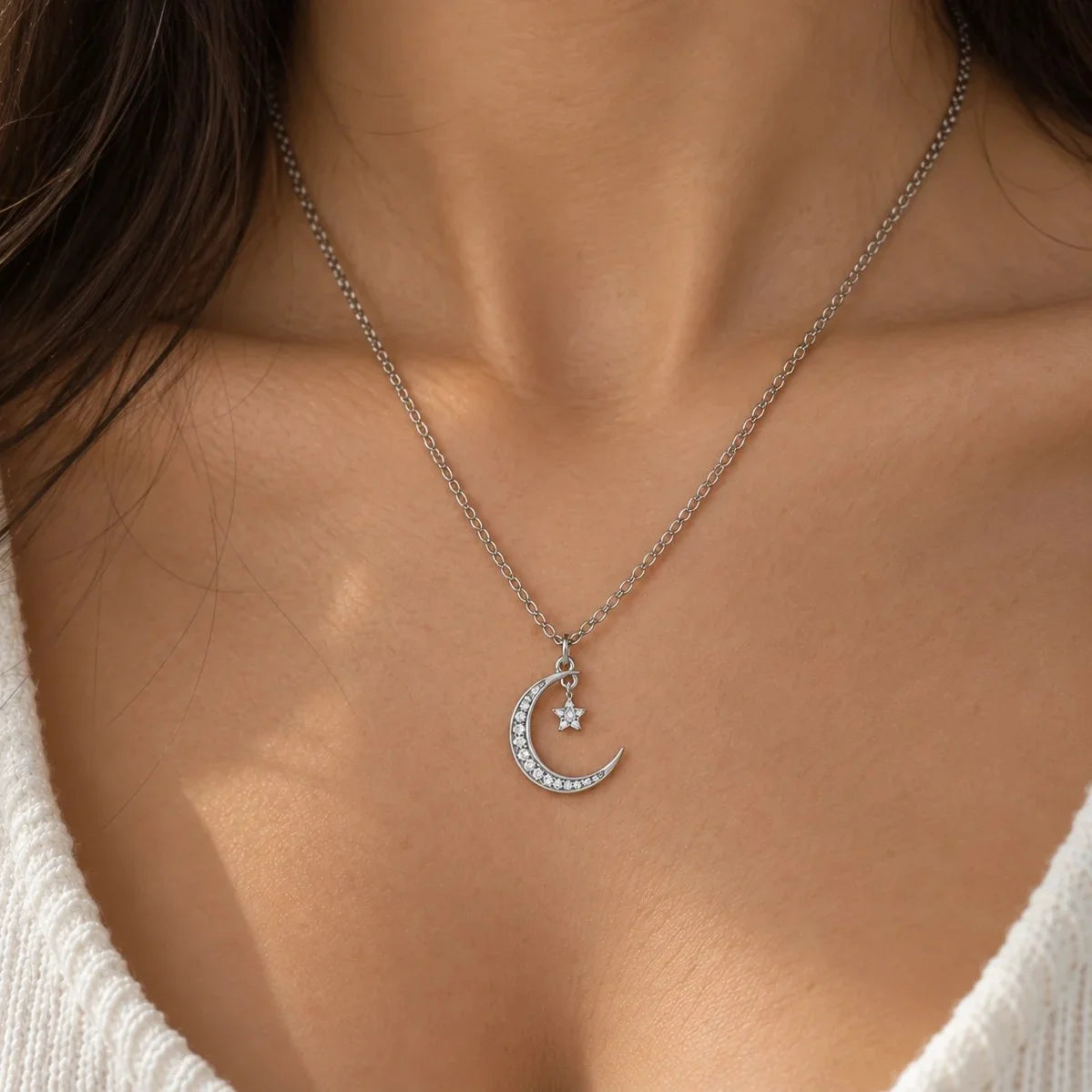 Moon_necklace_in_sterling_silver_with_a_small_star_charm_at_front_angle_view_wron_by_a_model
